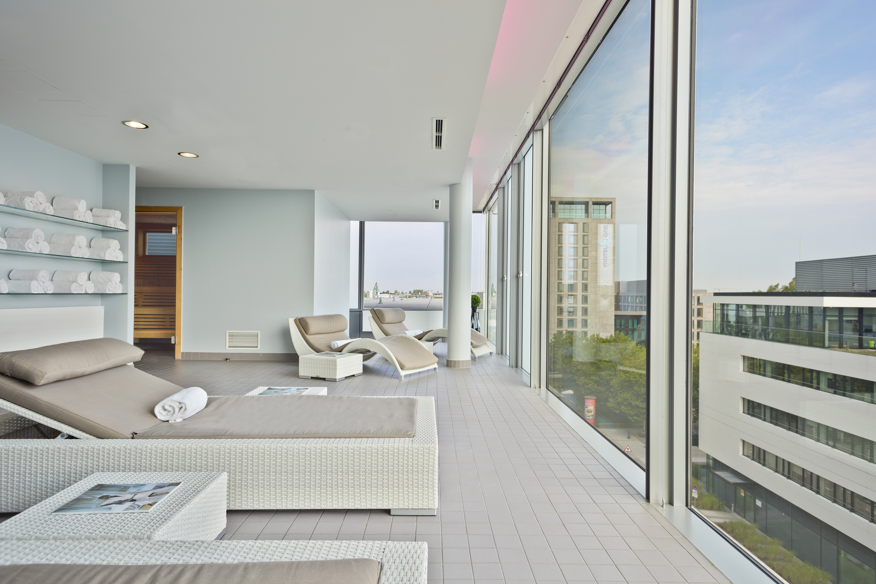Spa relaxation lounge with chaise lounges, sauna, and panoramic city view.