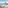 Beachfront balcony: rocking chair, palm trees, sandy beach, blue ocean.