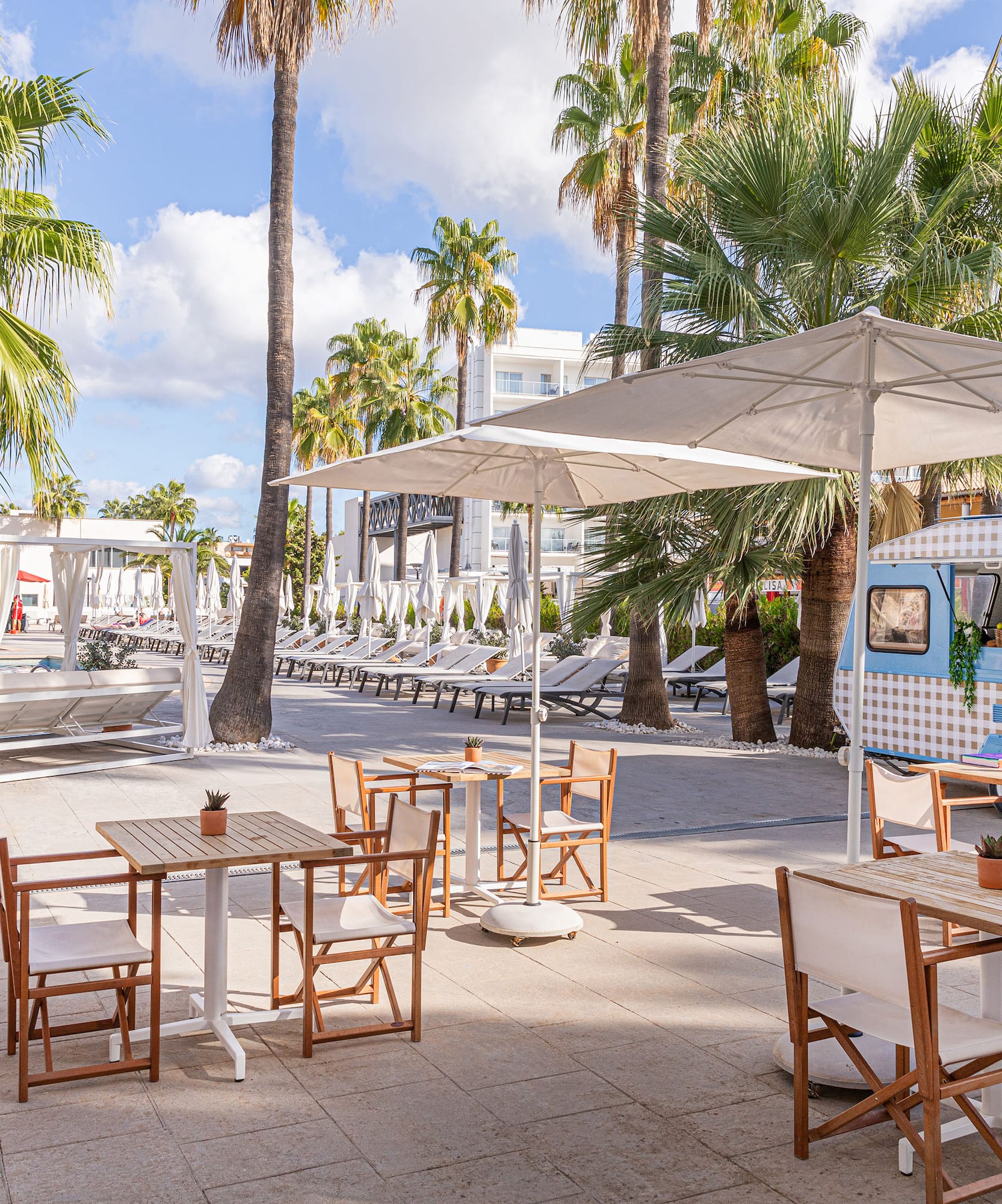 a tables and chairs outside with umbrellas and palm trees