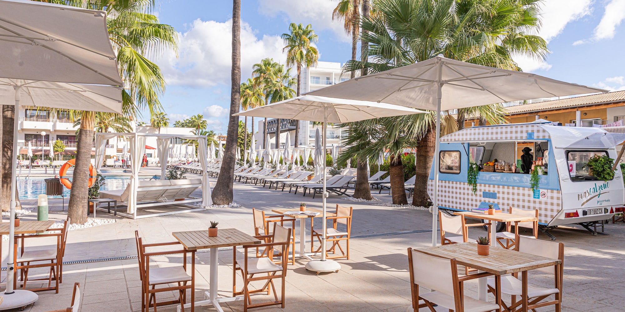 a tables and chairs outside with umbrellas and palm trees