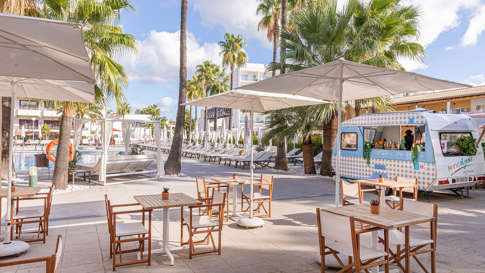 a tables and chairs outside with umbrellas and palm trees