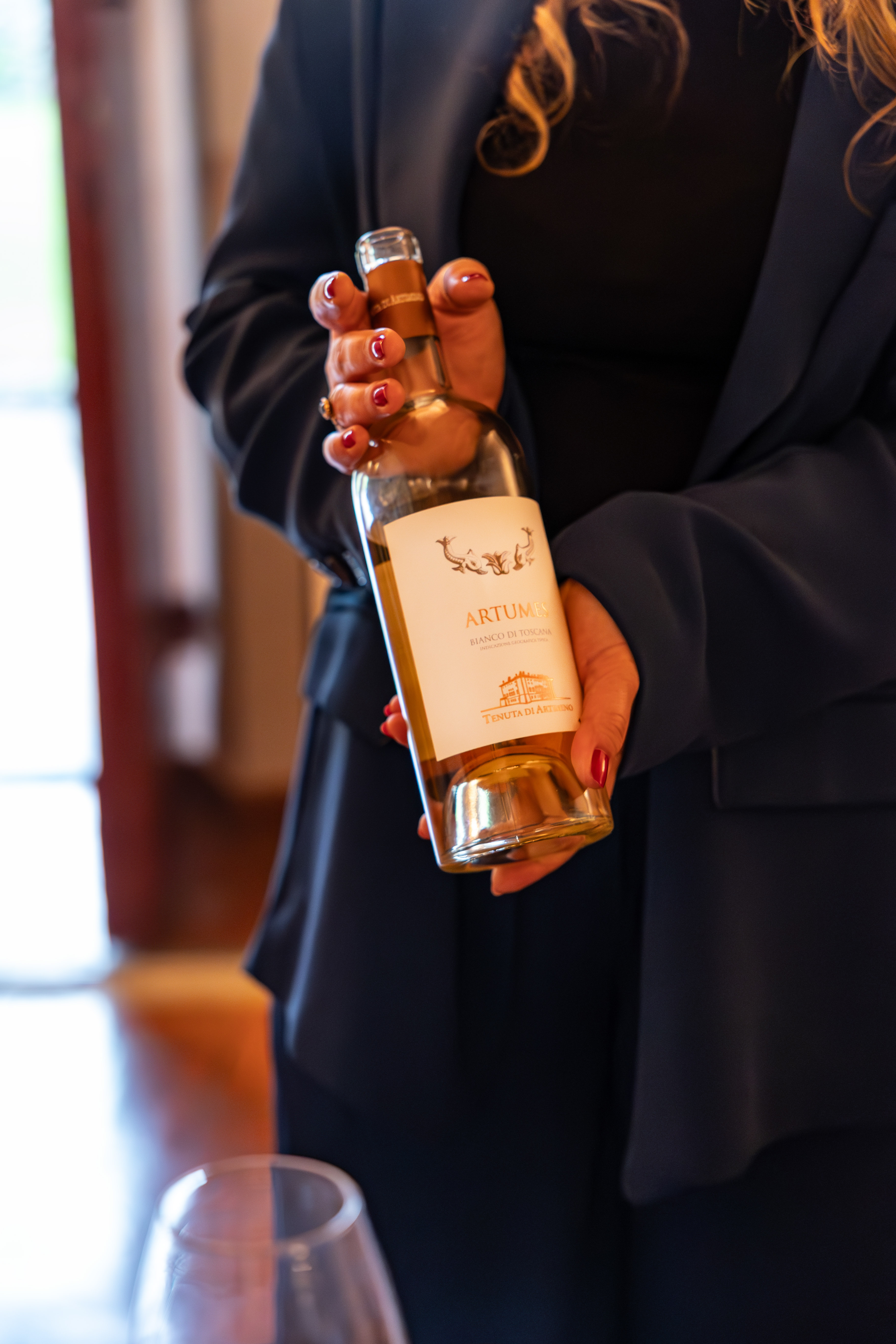 Artumes Bianco di Toscana white wine bottle held by hands.