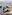Rocky coastal retreat with person by clear sea, straw umbrella, sunbeds.
