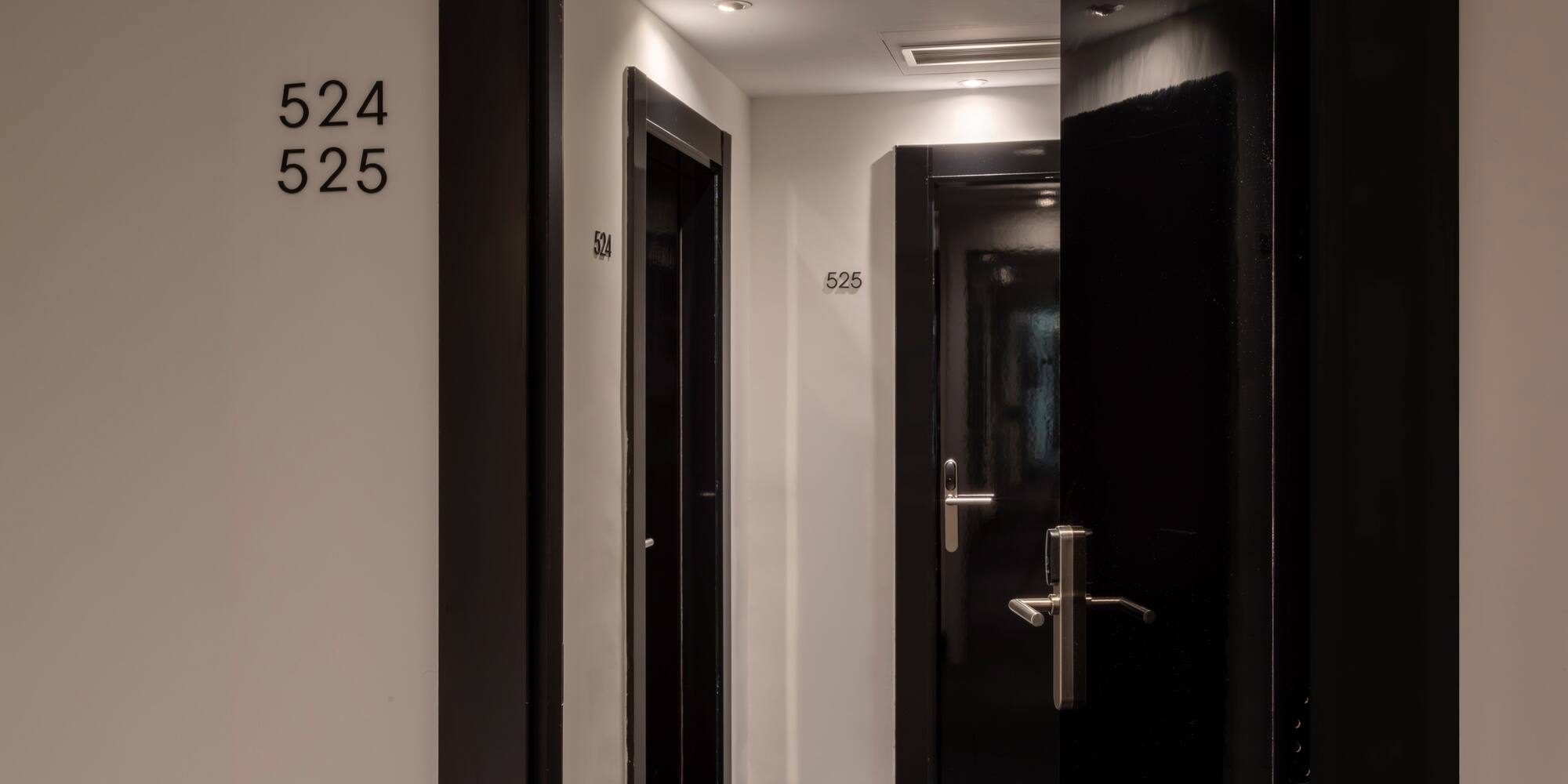 Modern hotel corridor with black doors, room numbers 524 and 525.