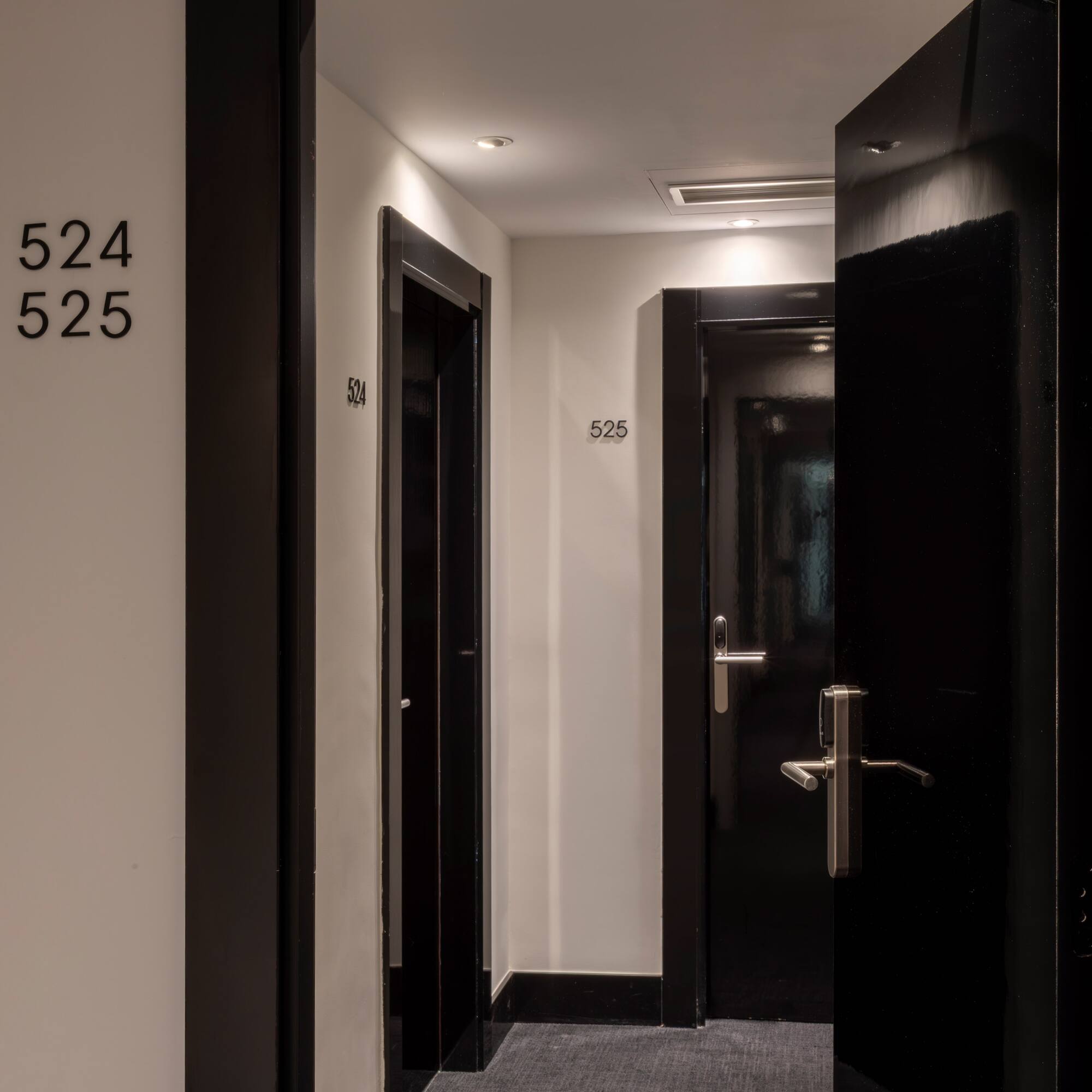 Modern hotel corridor with black doors, room numbers 524 and 525.