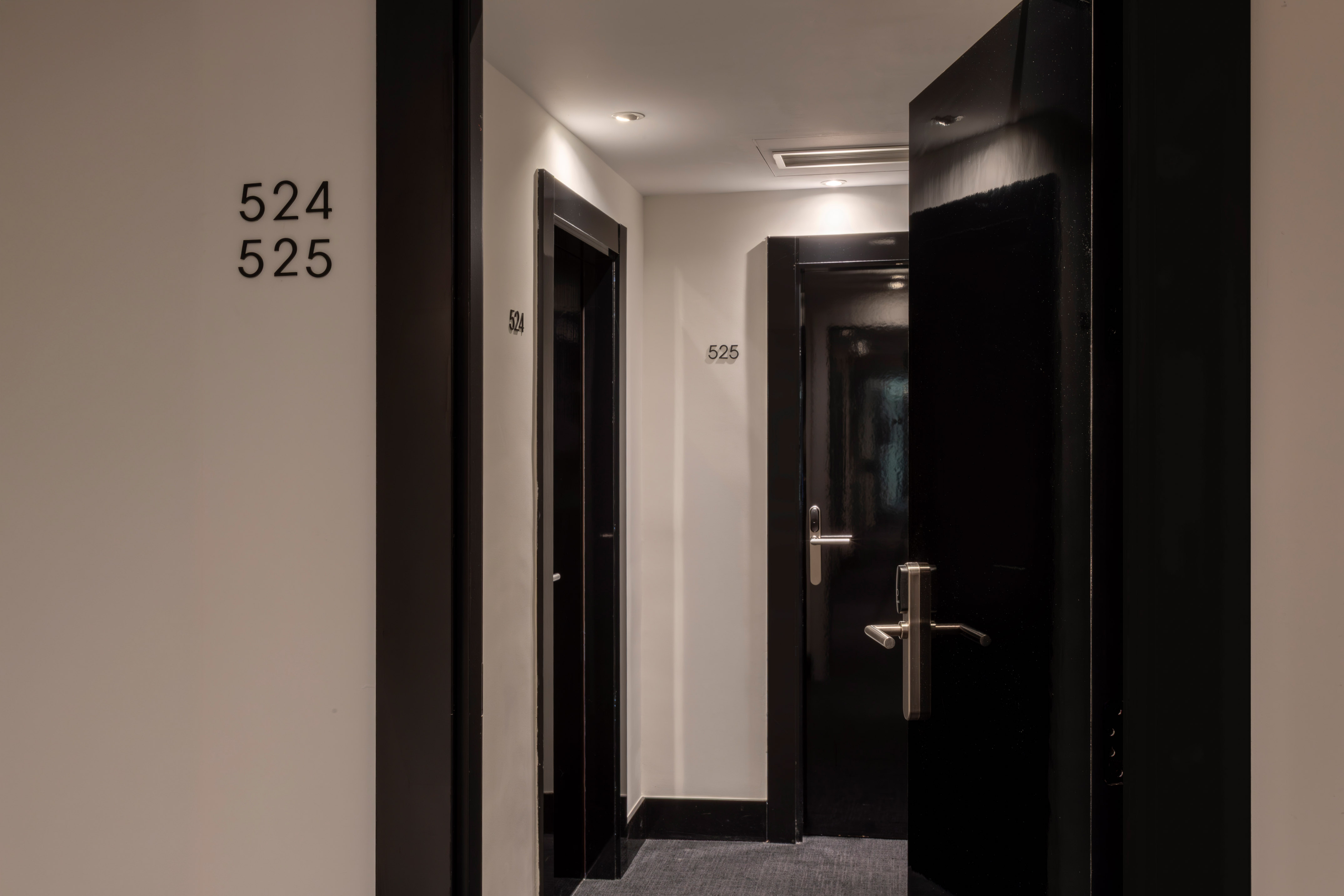 Modern hotel corridor with black doors, room numbers 524 and 525.
