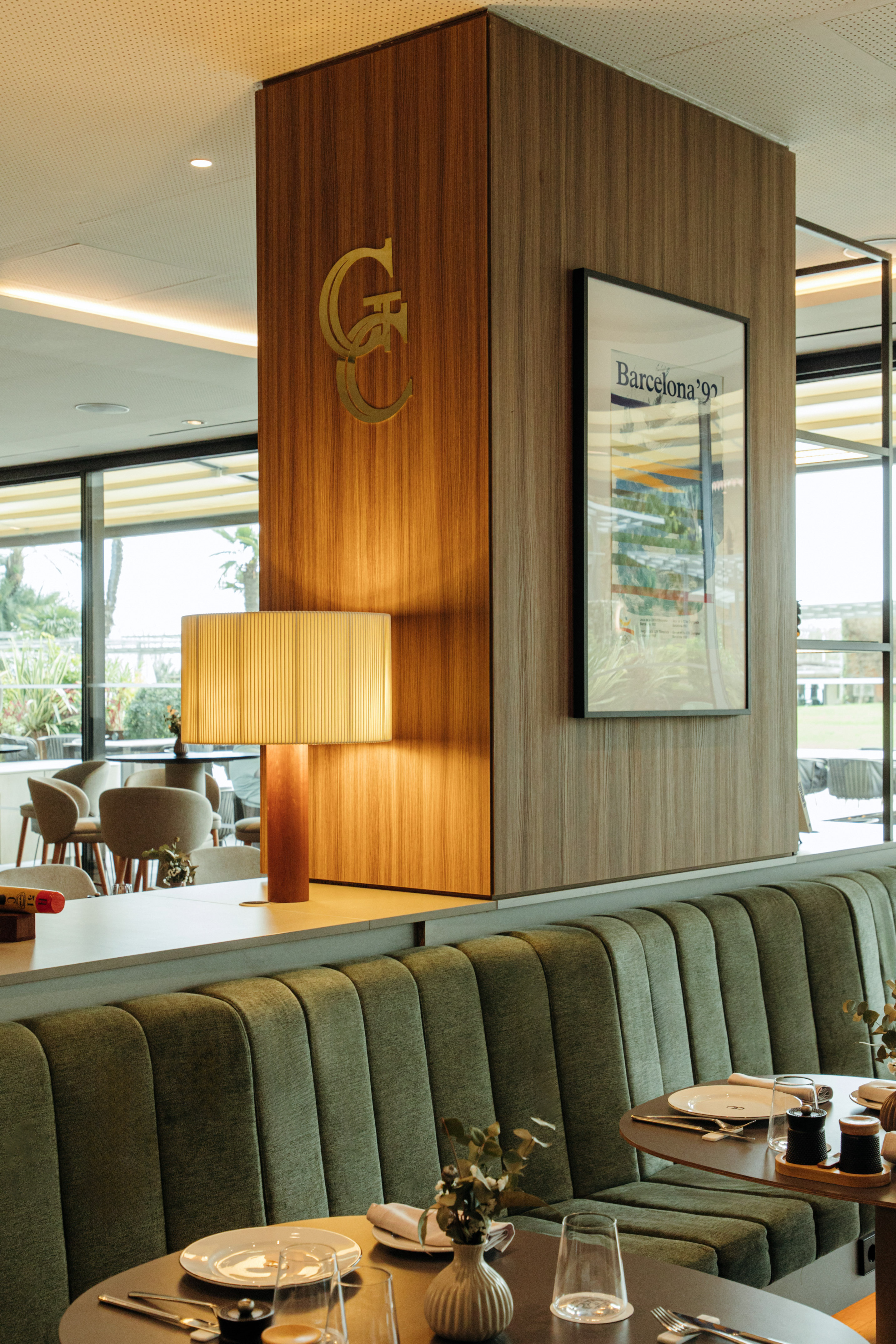 Green booth seating, wooden restaurant wall with Barcelona '92 poster.
