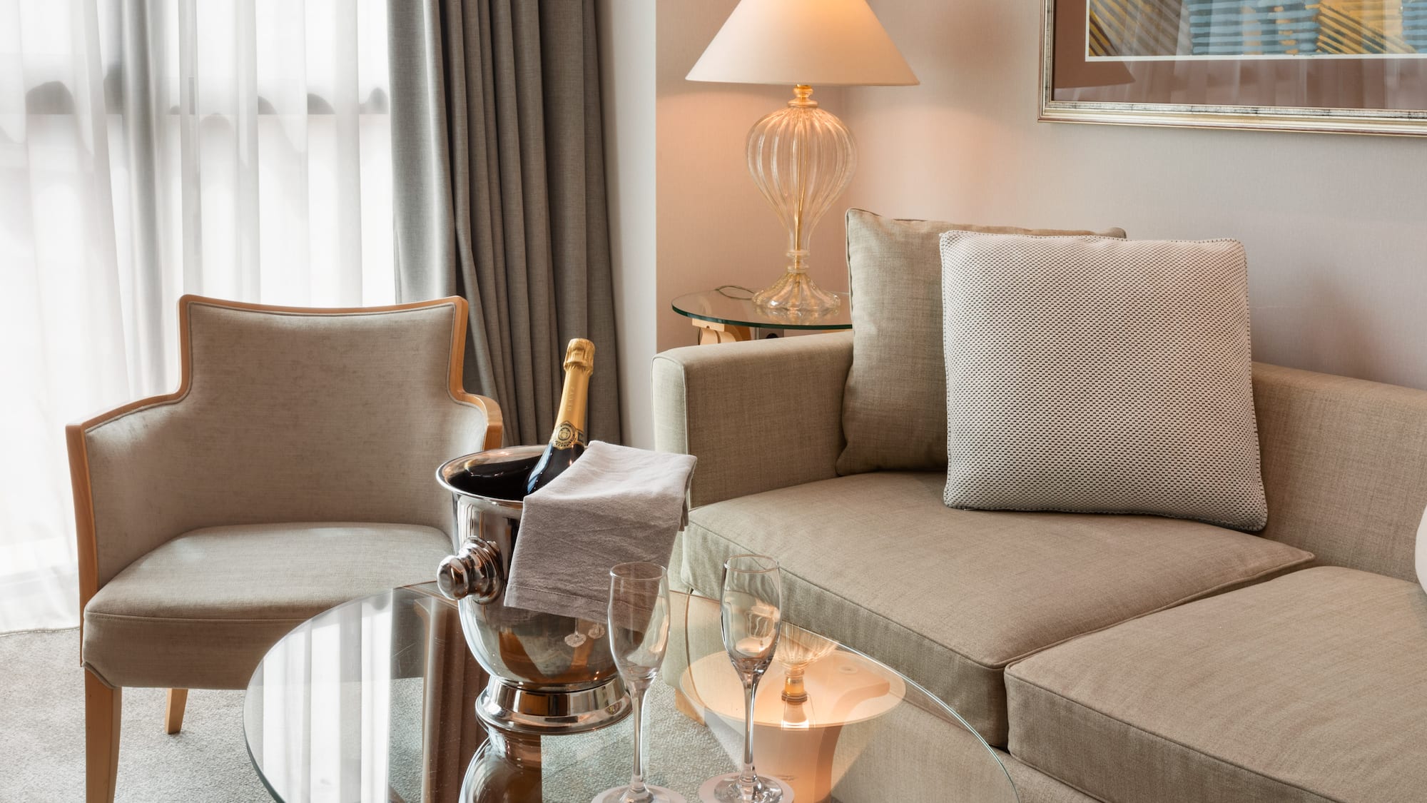 Hotel suite living area with champagne bucket, sofa, and armchair.
