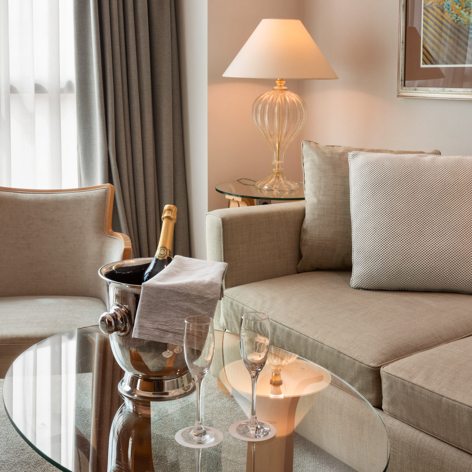 Hotel suite living area with champagne bucket, sofa, and armchair.