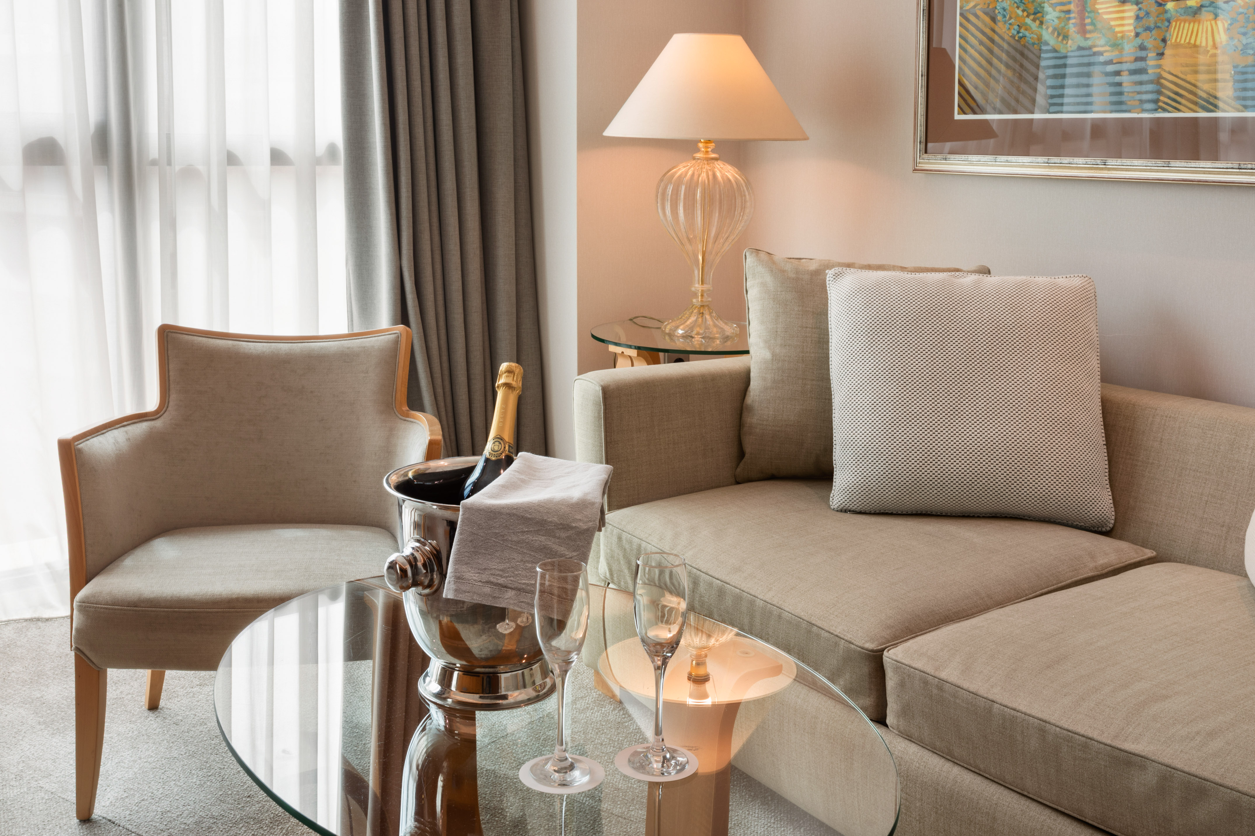 Hotel suite living area with champagne bucket, sofa, and armchair.