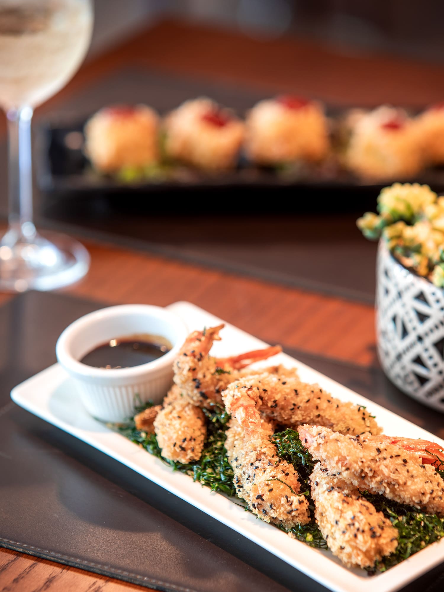 Platter of crispy sesame fried shrimp with dipping sauce and wine.