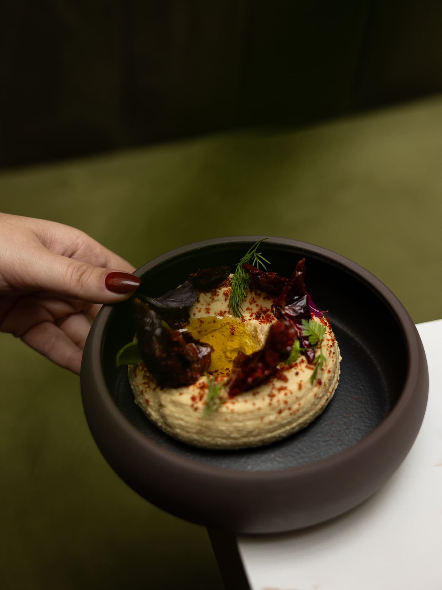 a person holding a bowl of hummus