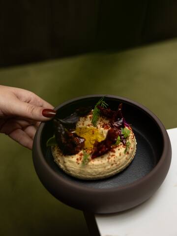 a person holding a bowl of hummus