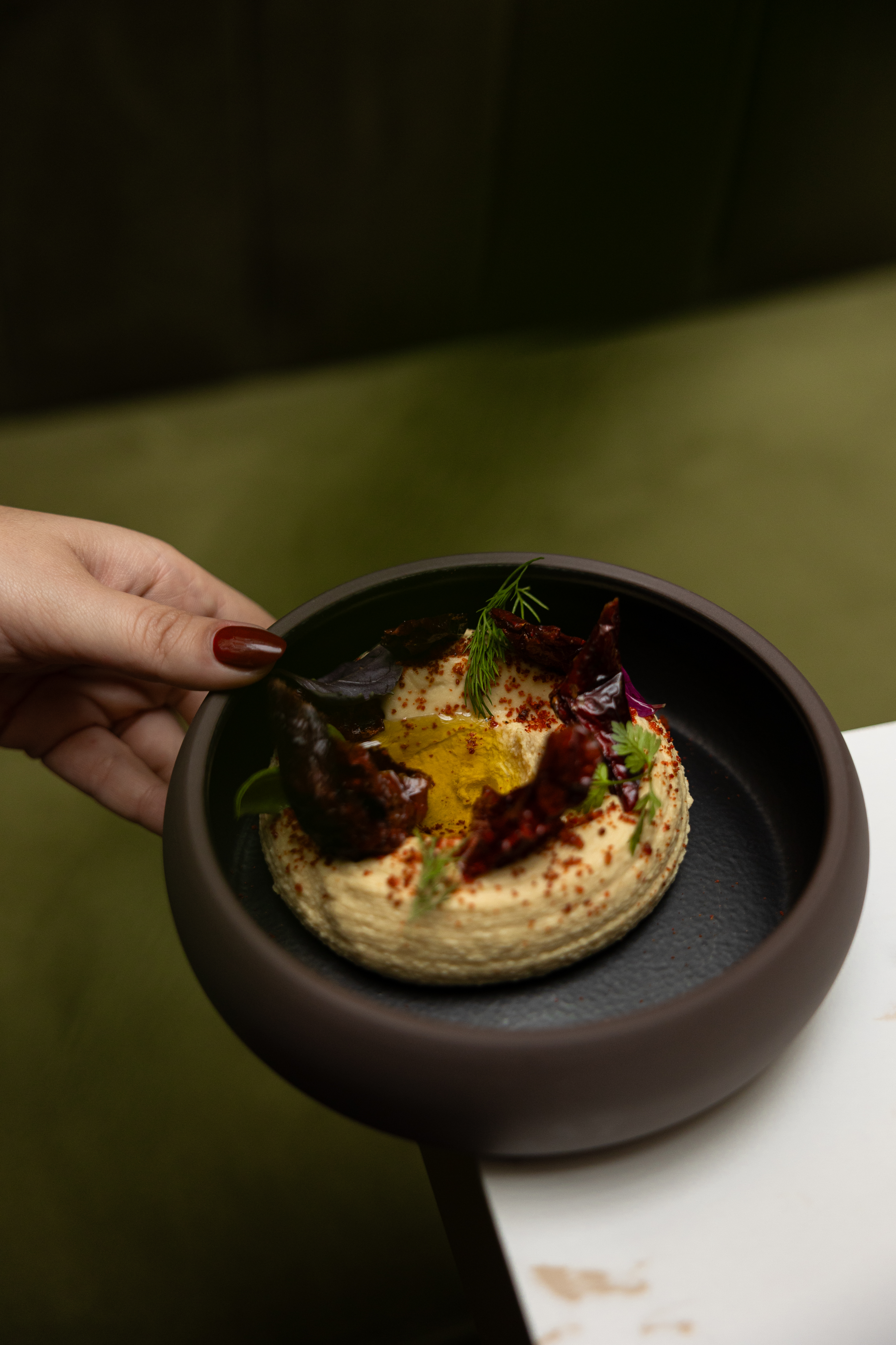Hummus bowl with sun-dried tomatoes, olive oil, herbs, and red spice.