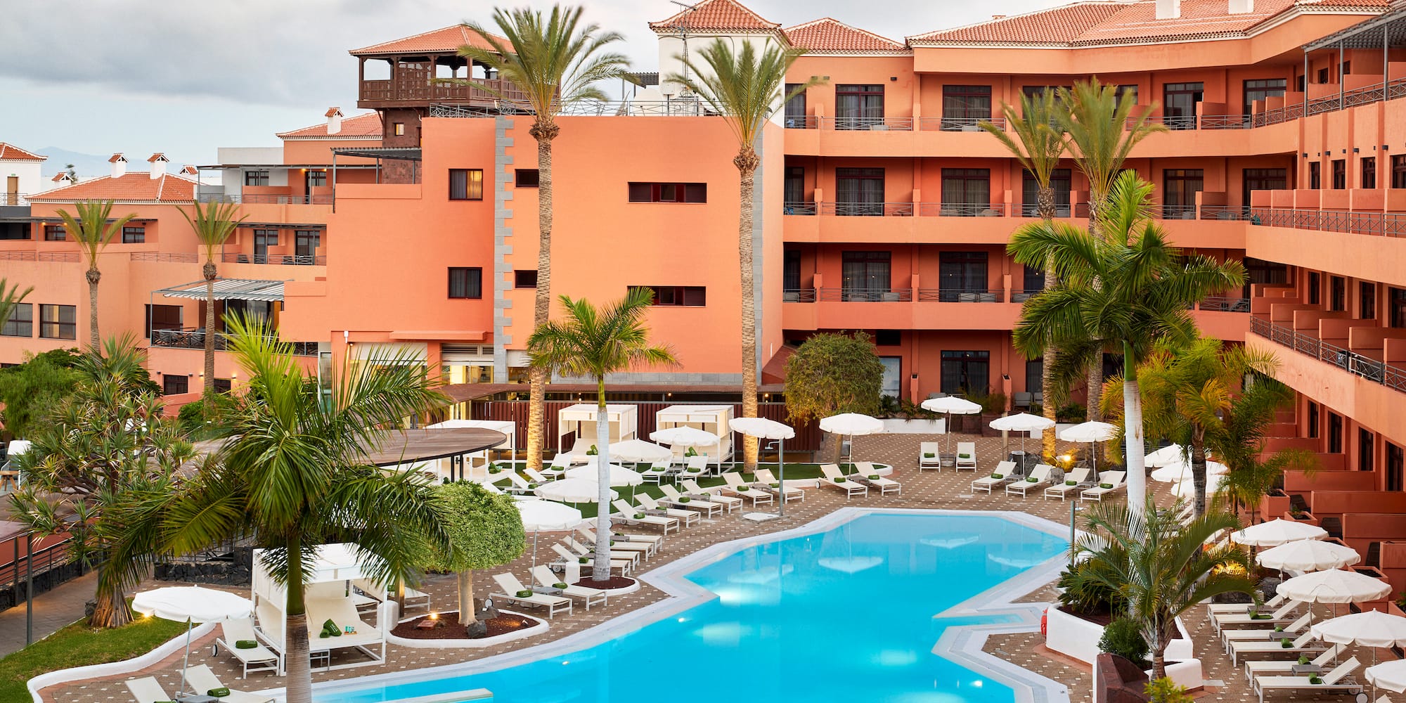 a pool with palm trees and a building