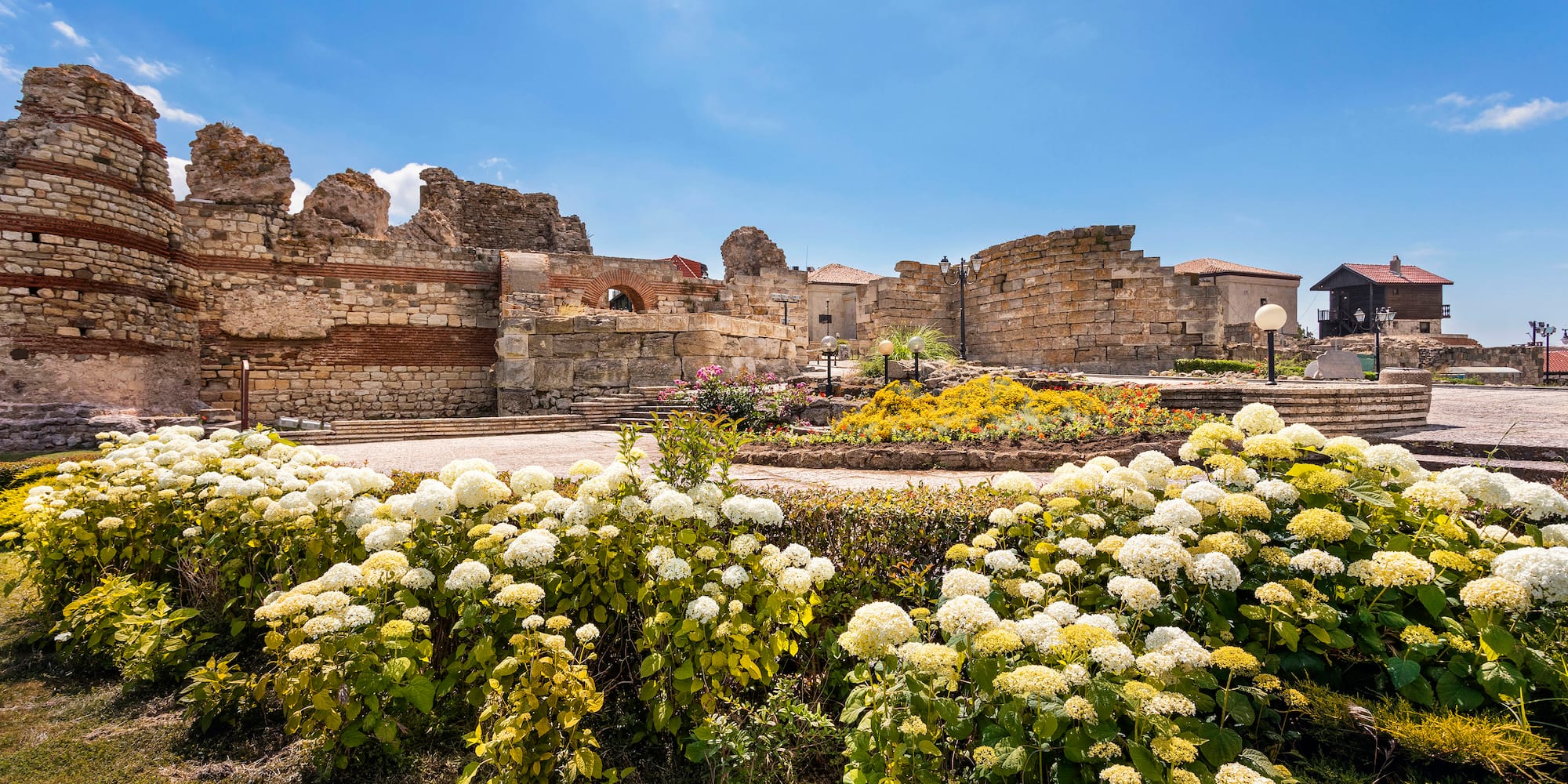 a garden with flowers in front of a stone building