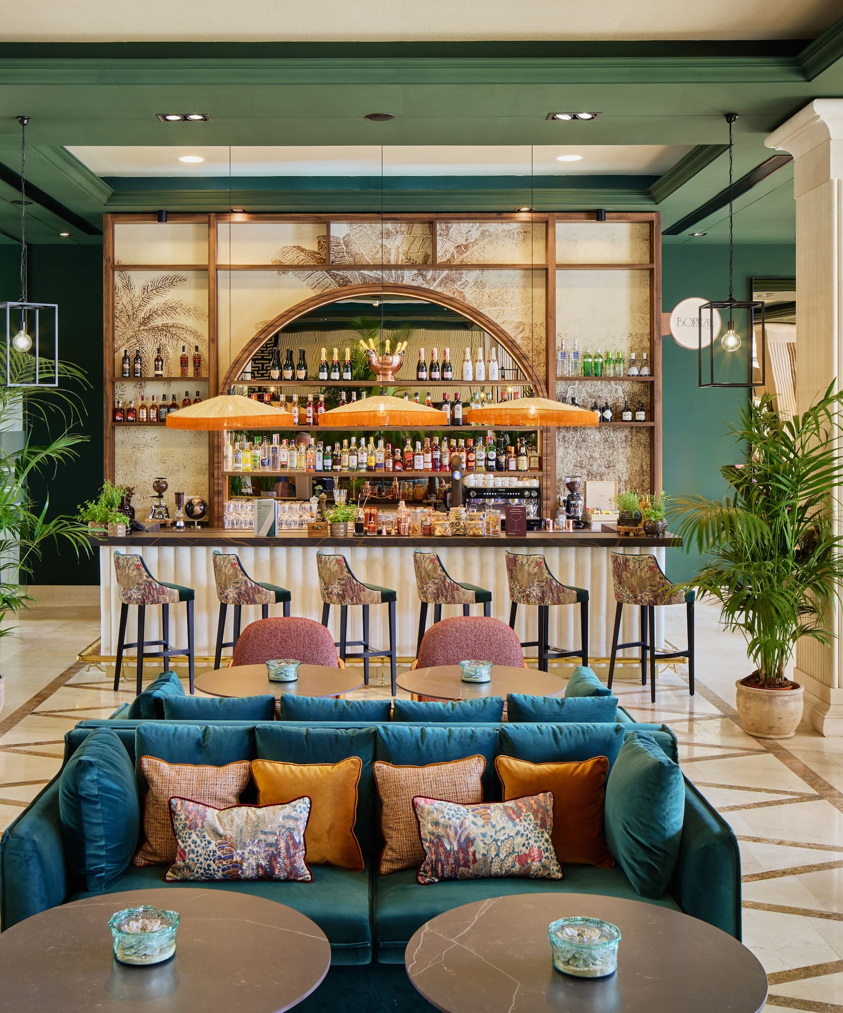 Stylish hotel bar lounge with tropical decor, green walls, and elegant seating.