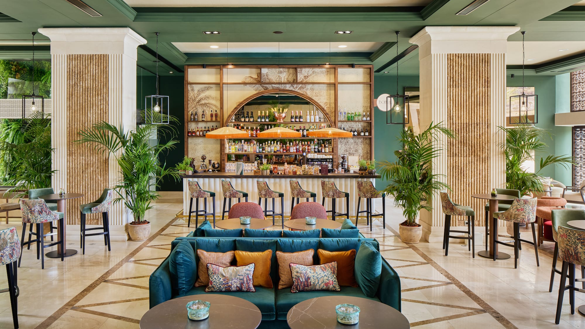 Tropical-themed hotel bar and lounge with green decor and plush seating.