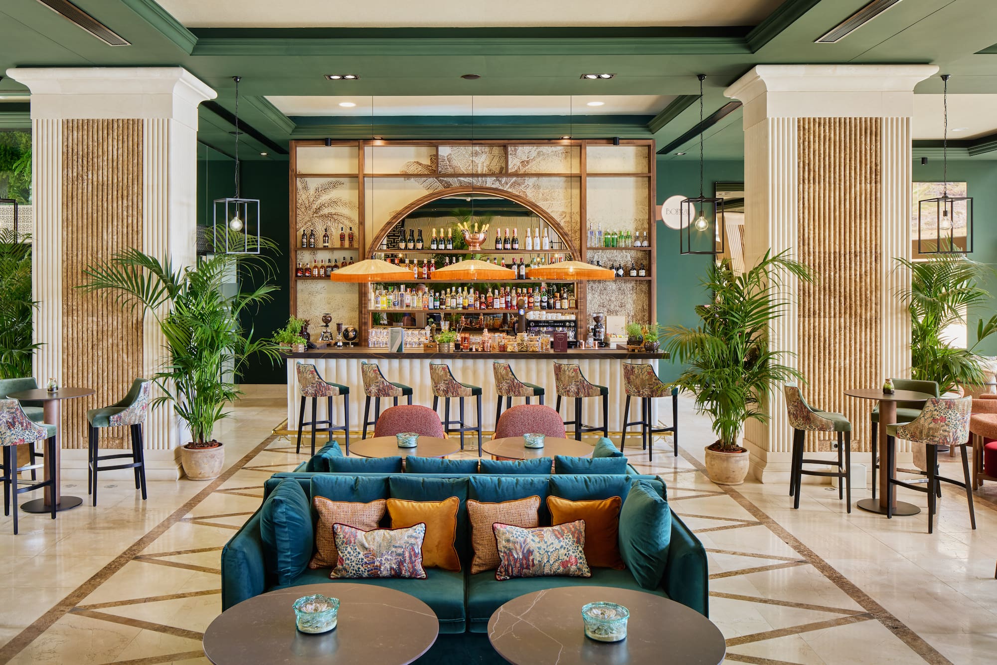 Luxurious hotel lobby bar with tropical decor, green walls, and plush seating.