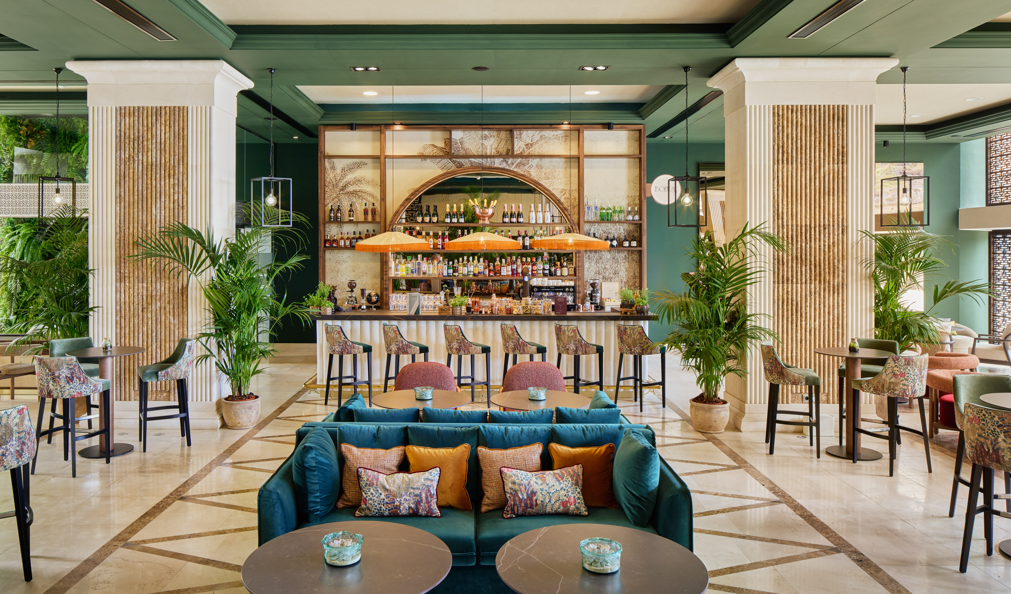 Stylish hotel bar lounge with tropical decor, green walls, and elegant seating.