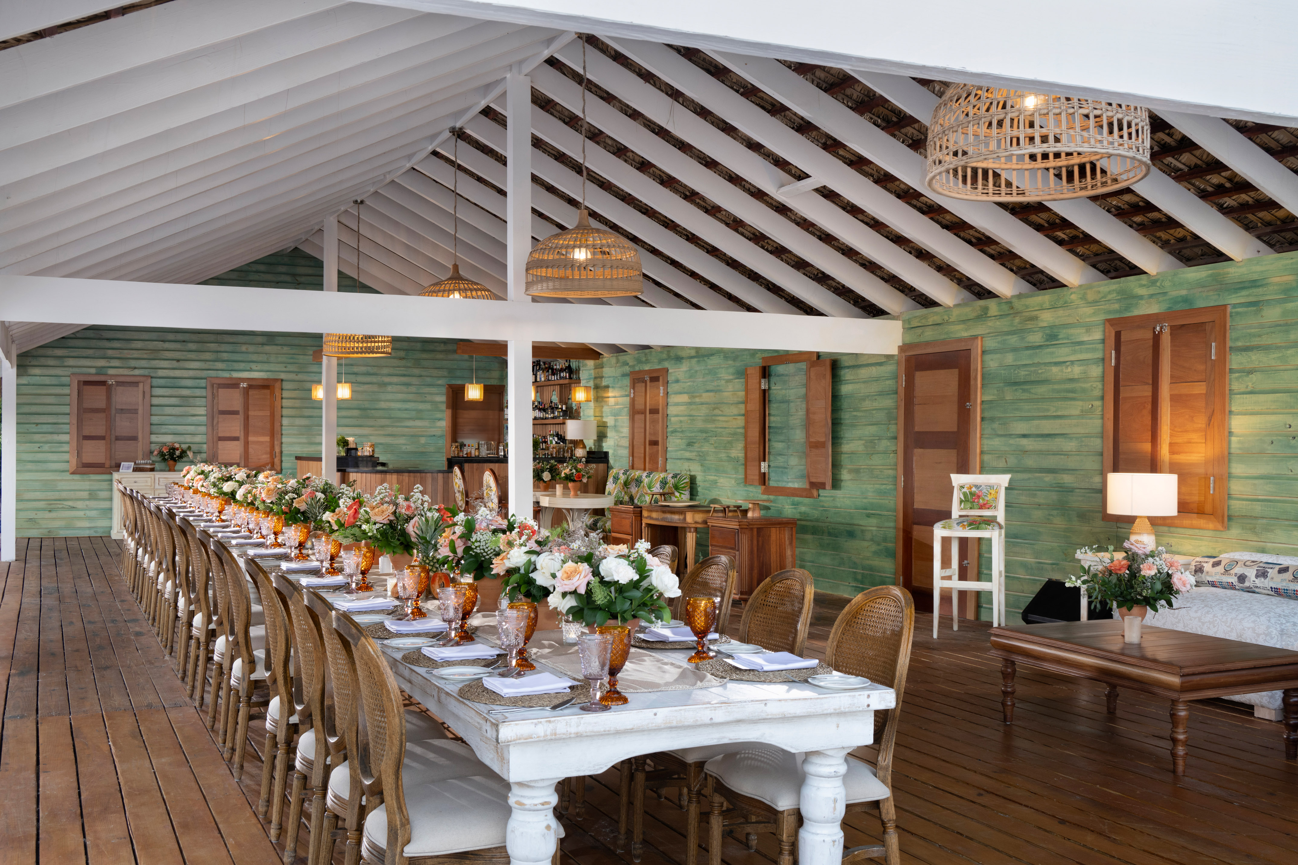 Long tropical dining table set for a rustic elegant event with flowers.