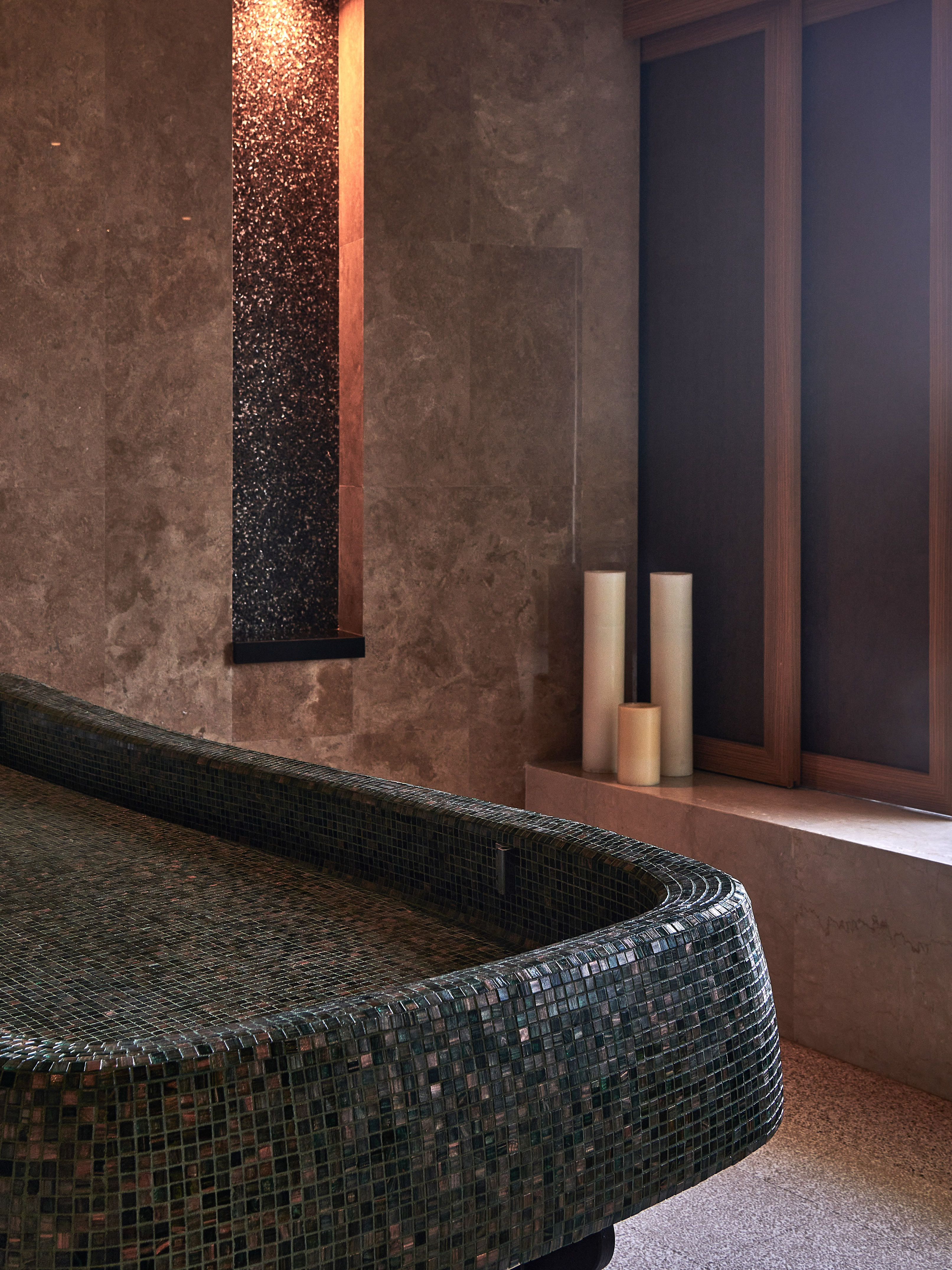 Serene spa room with mosaic treatment bed, sparkling wall feature, and candles.