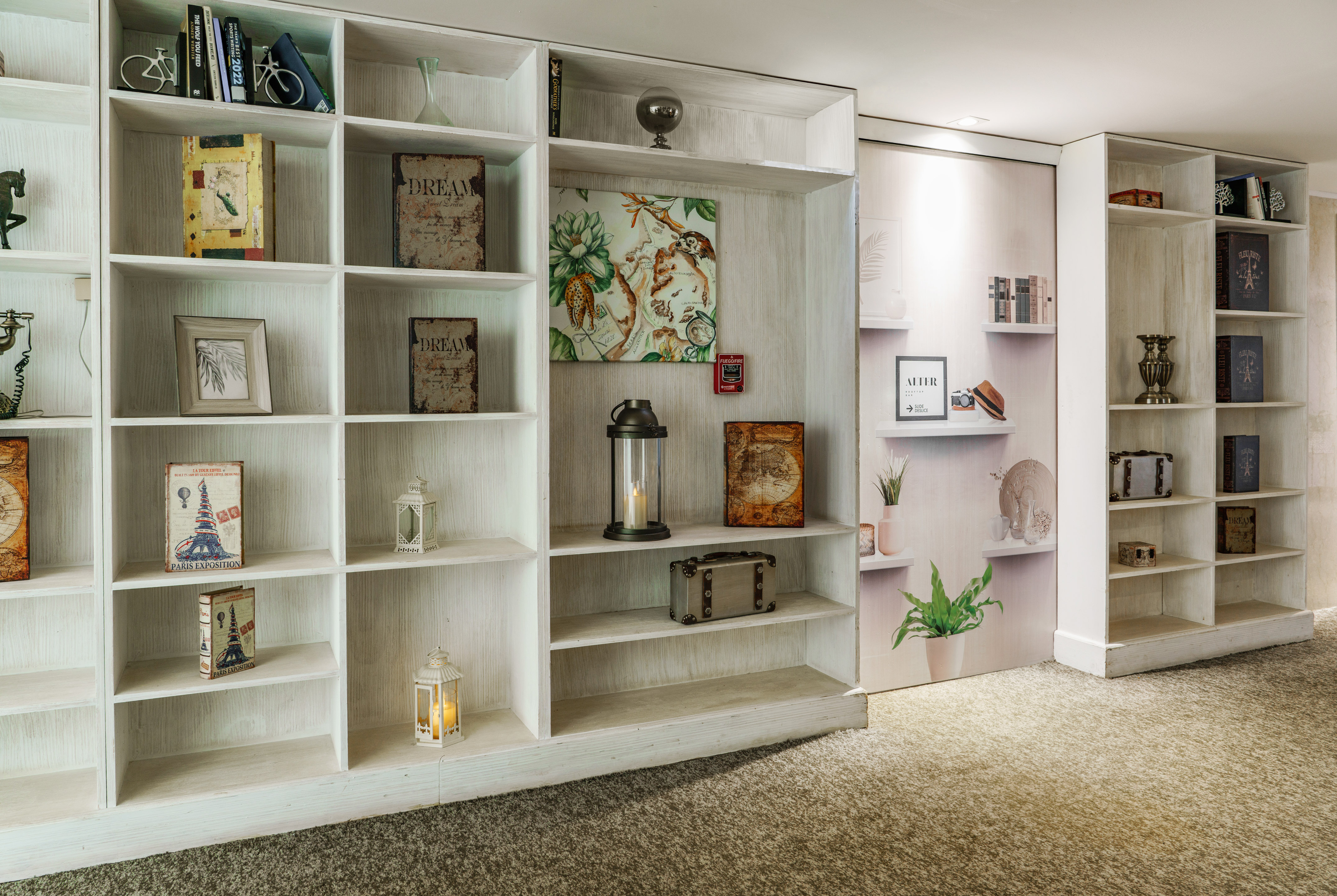 White distressed bookshelf displaying books, vintage decor, and lanterns.