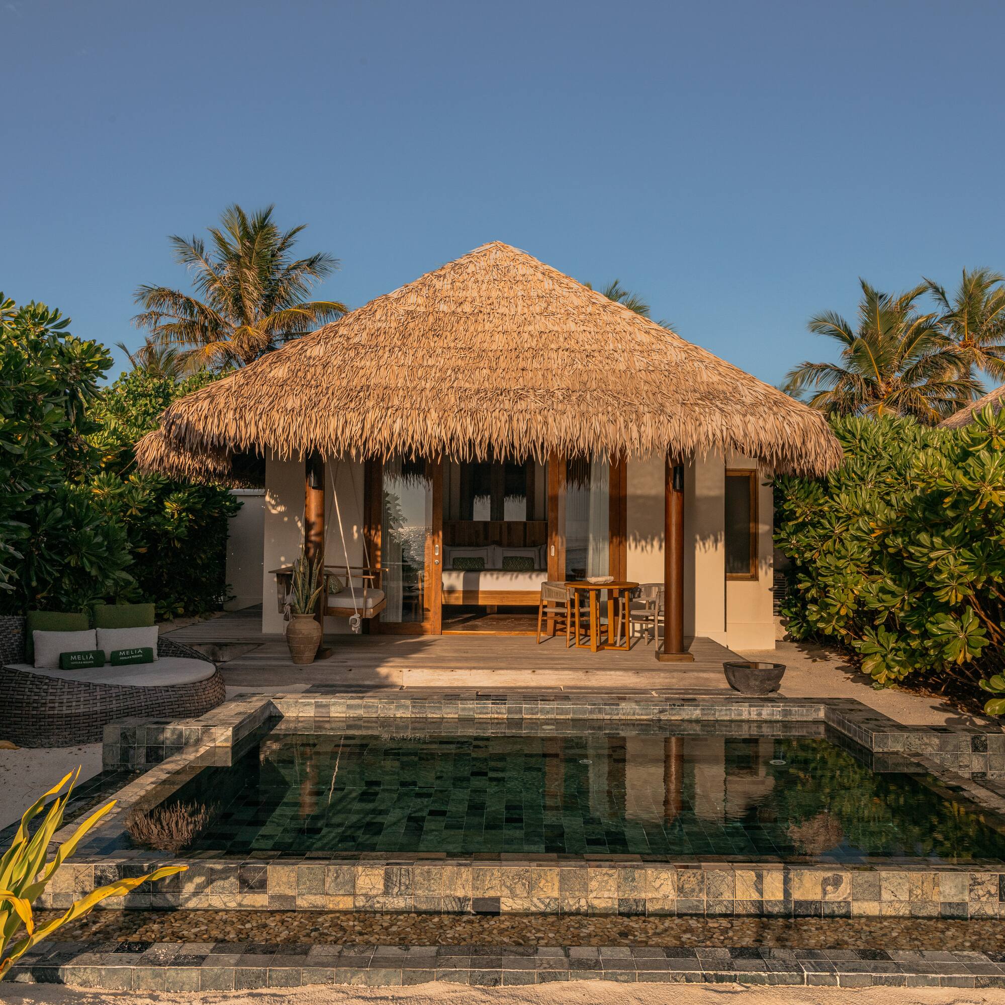 a building with a pool and a thatched roof