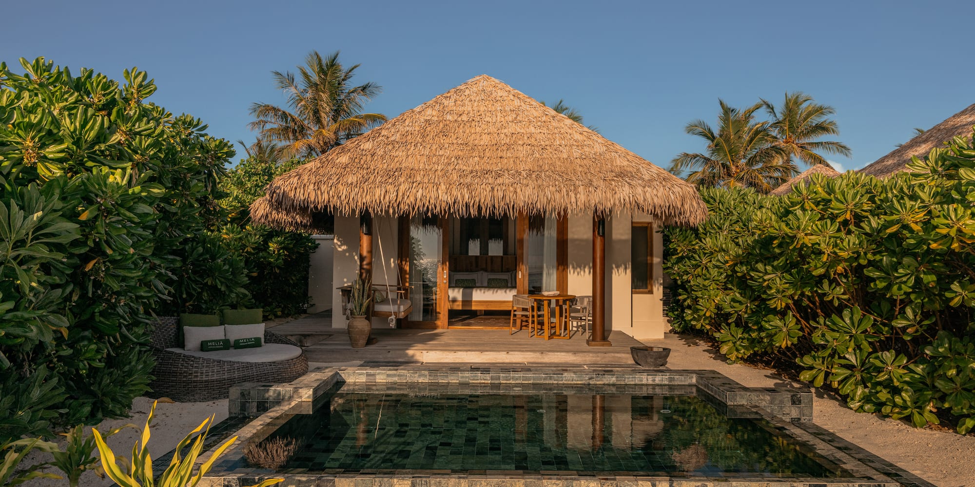 a building with a pool and a thatched roof