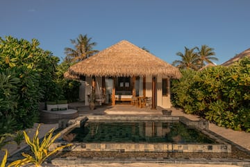 a building with a pool and a thatched roof