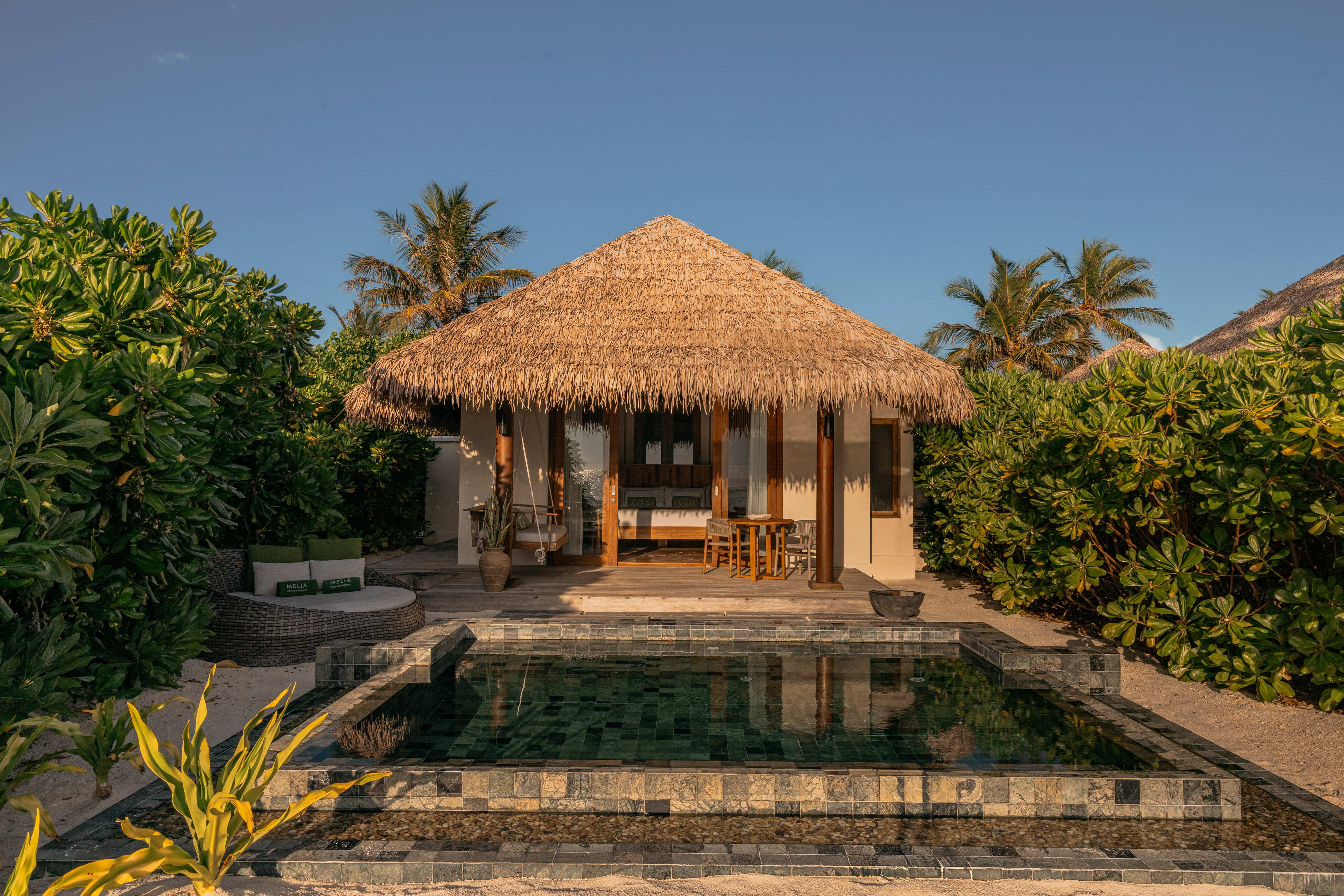 a building with a pool and a thatched roof