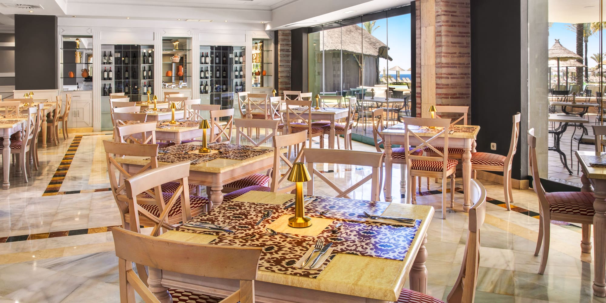 Elegant hotel restaurant with marble floors, wine display, and beach view.