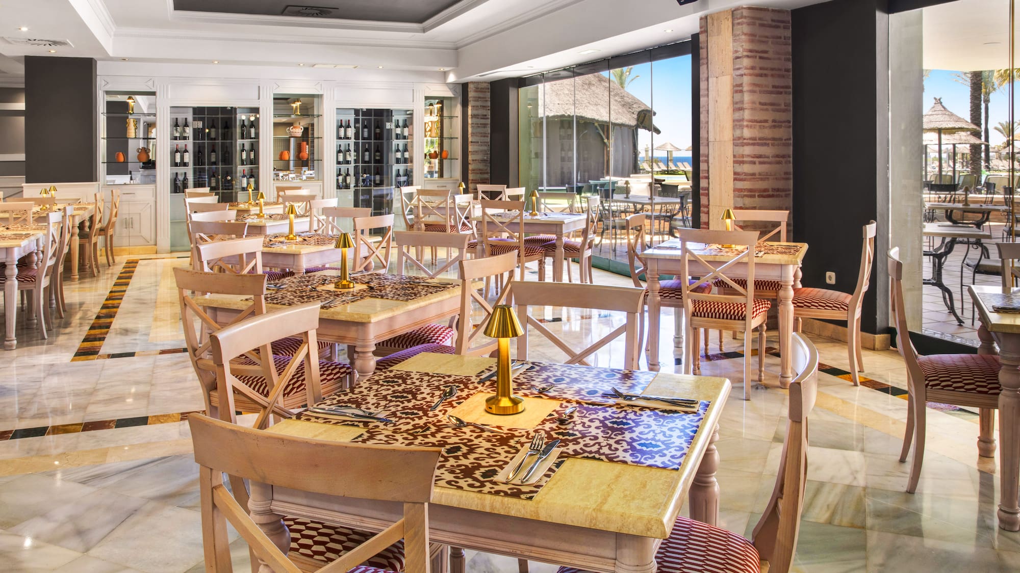 Elegant hotel restaurant with marble floors, wine display, and beach view.