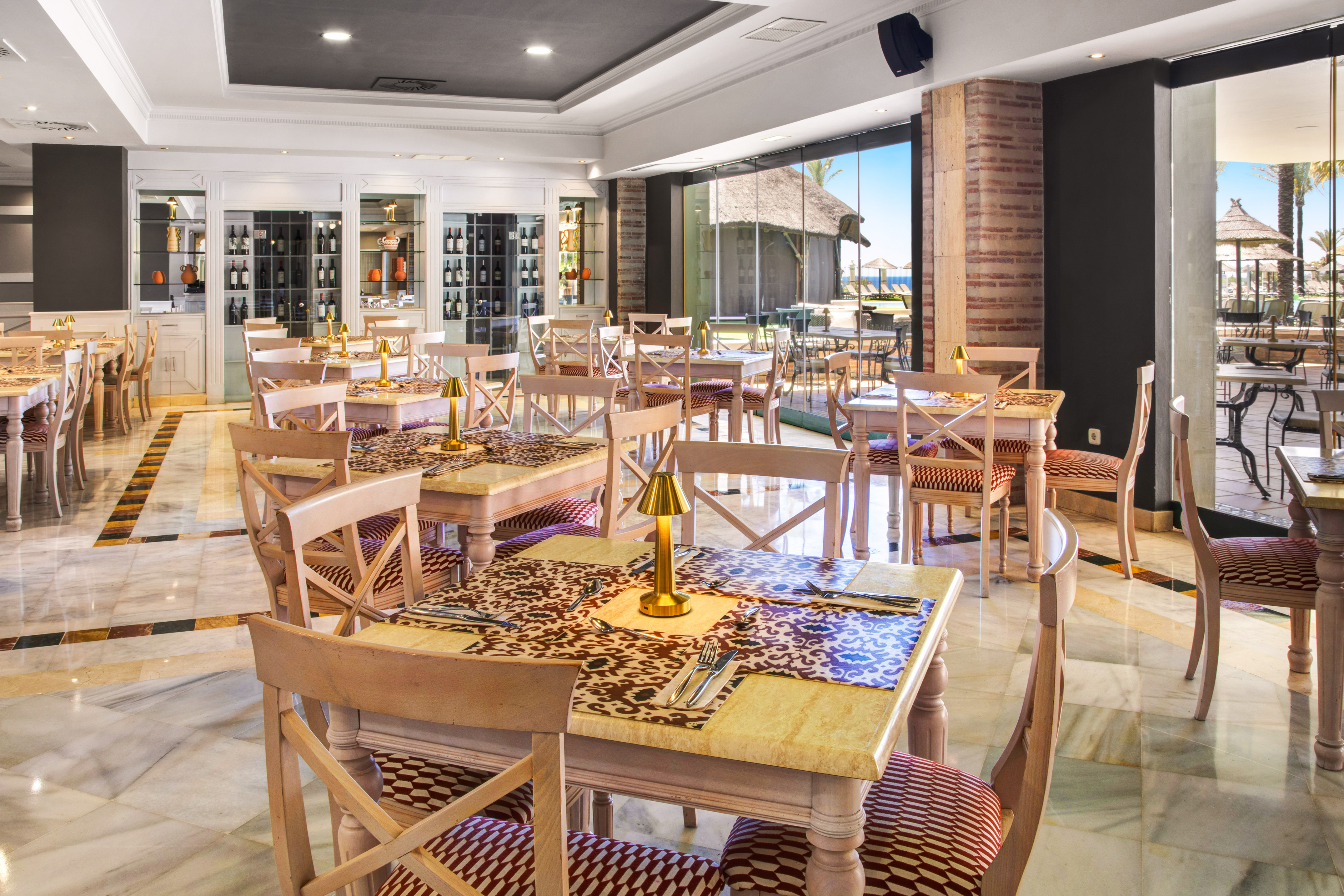 Elegant hotel restaurant with marble floors, wine display, and beach view.