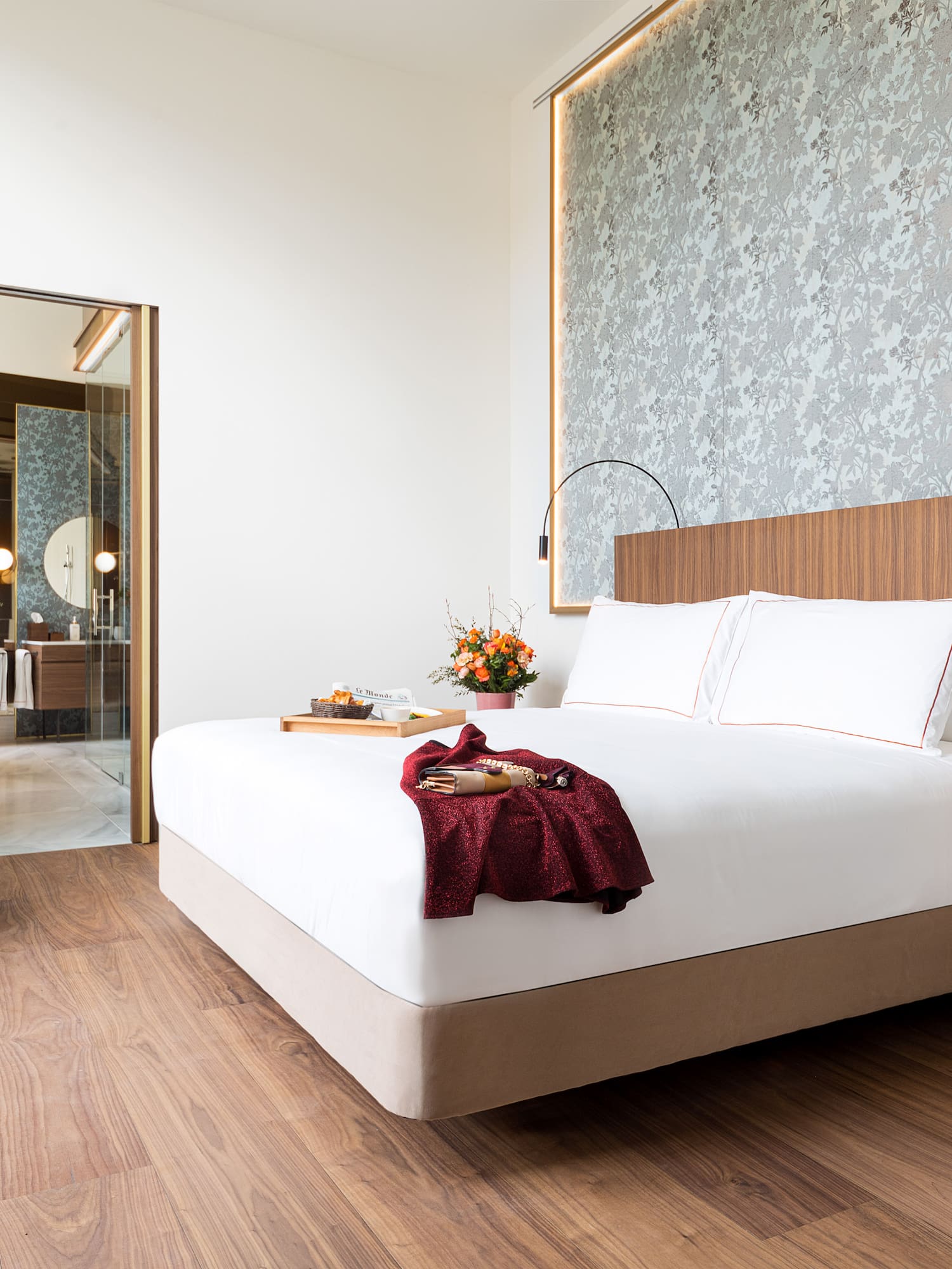 Modern luxury hotel room with king bed, wood floor, and open bathroom.