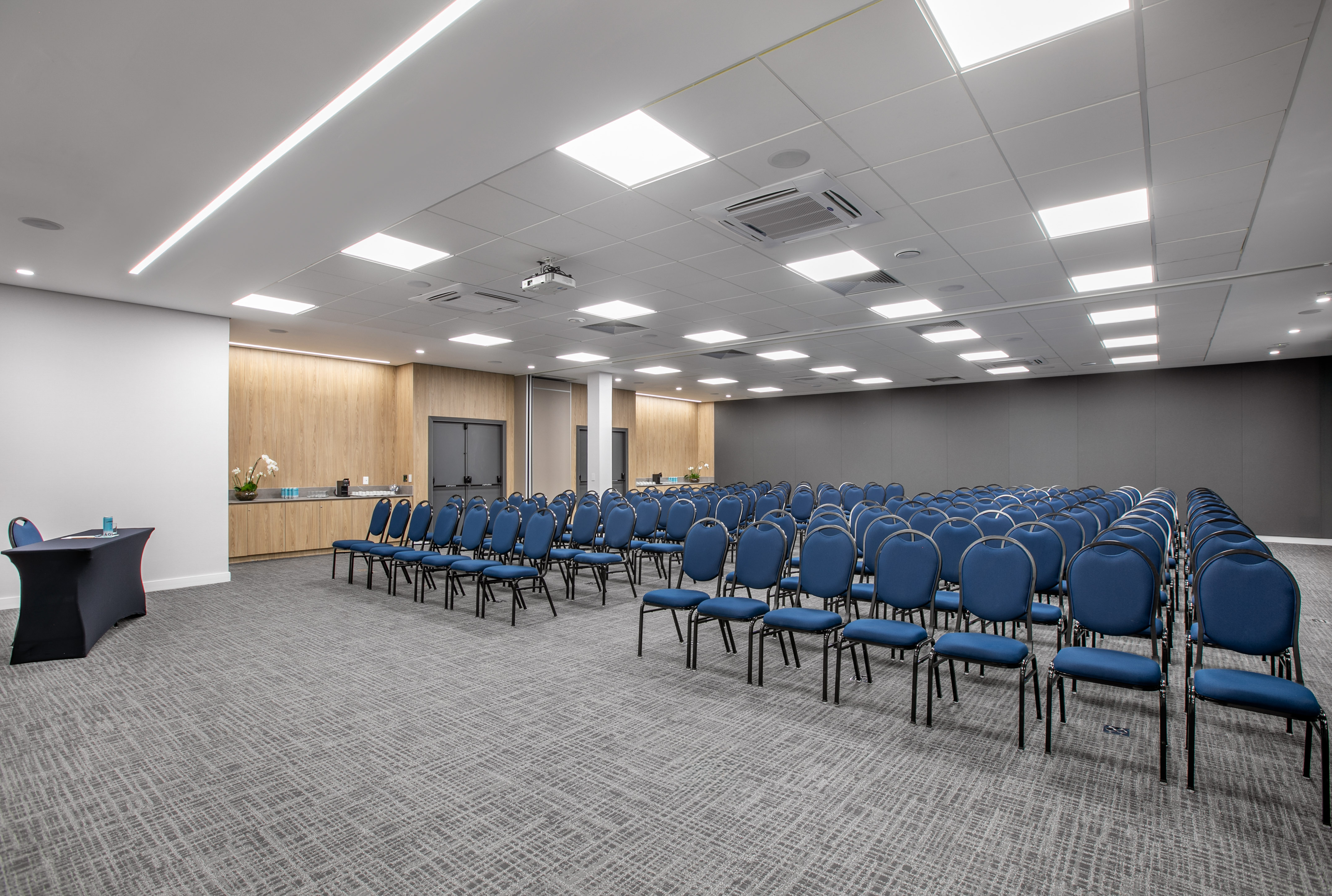 Empty modern conference room with blue chairs and ceiling projector.