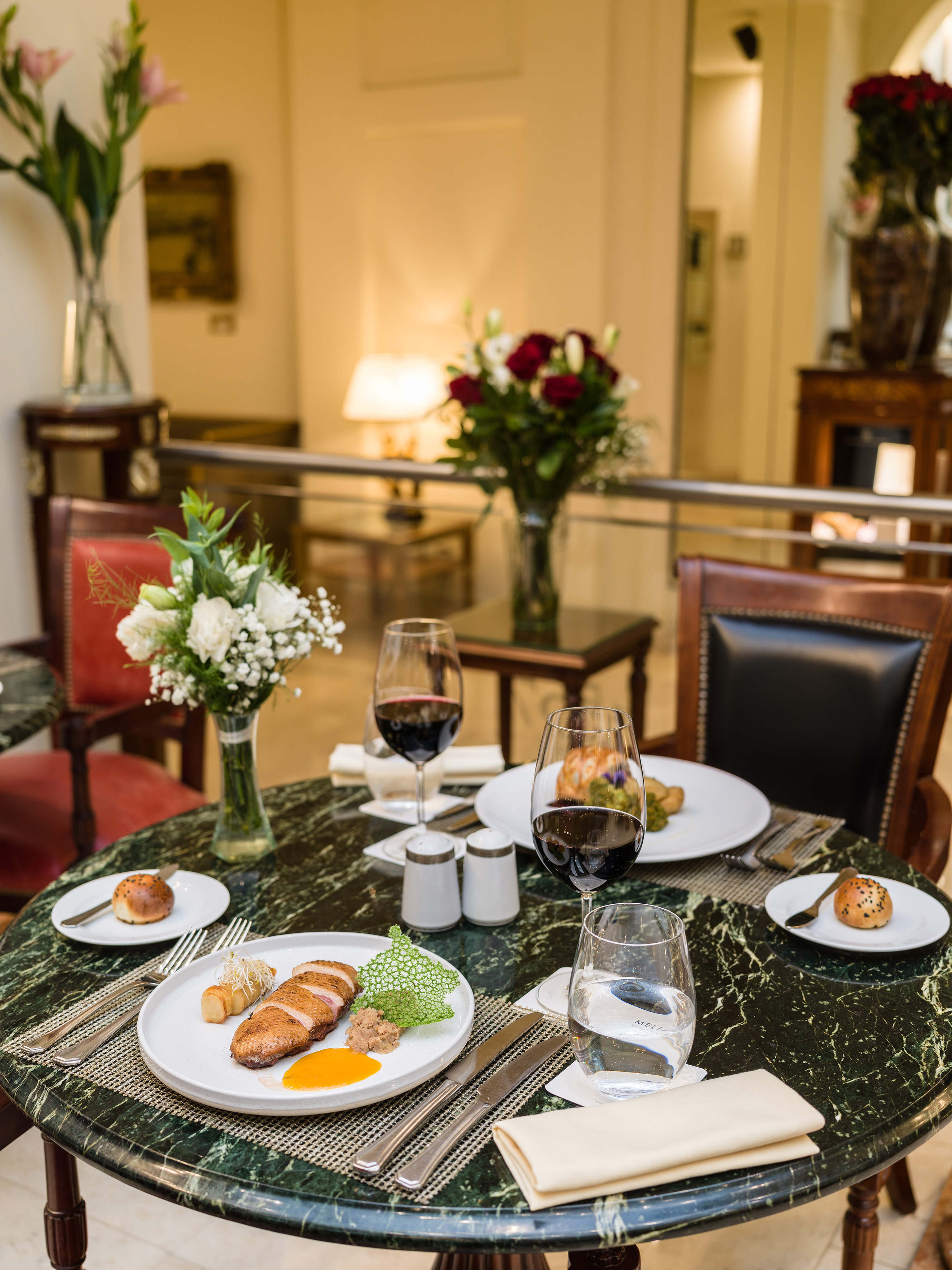 Elegant duck breast and red wine dinner on a green marble table.