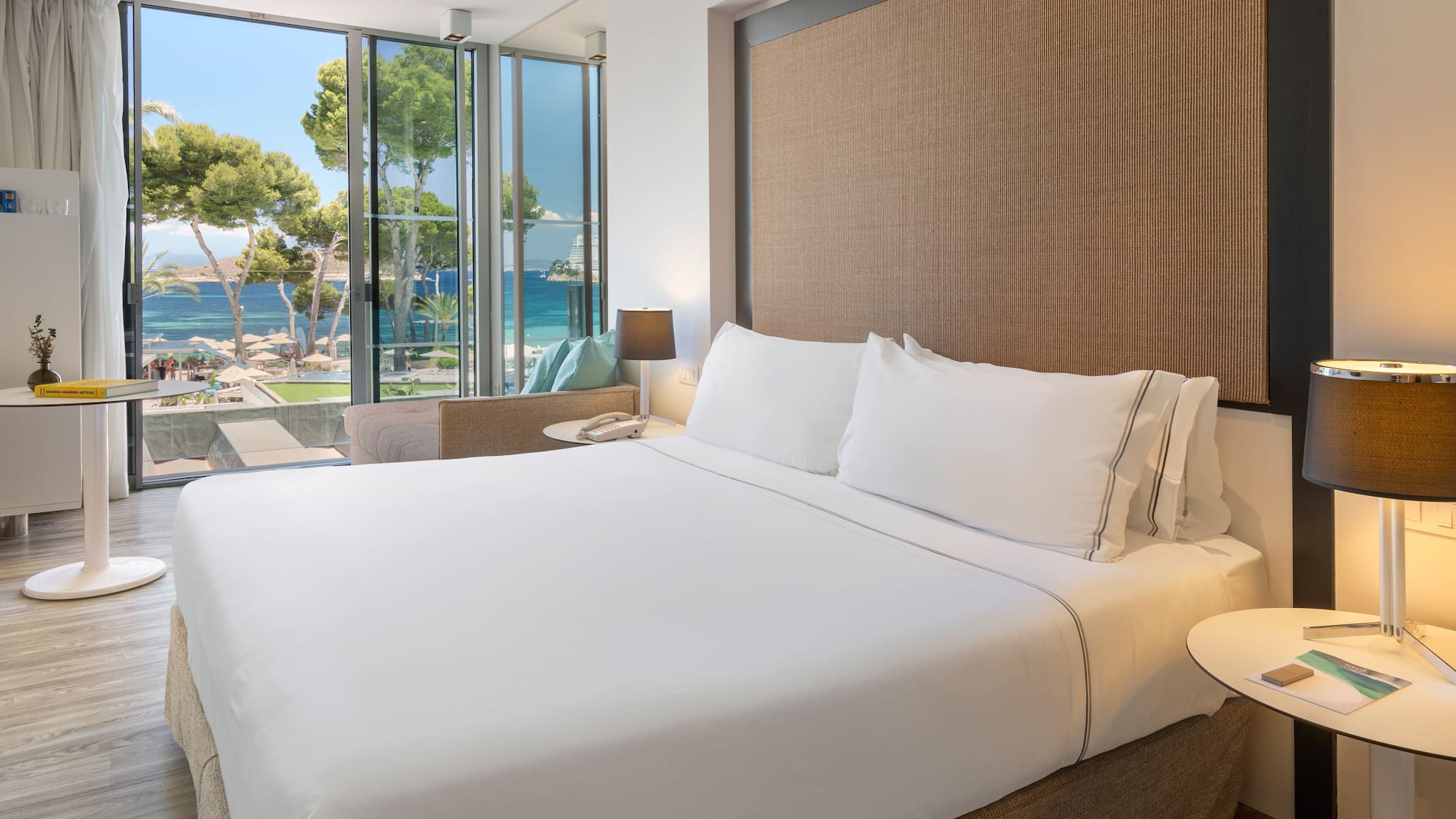 a bed with white sheets and a table next to a window