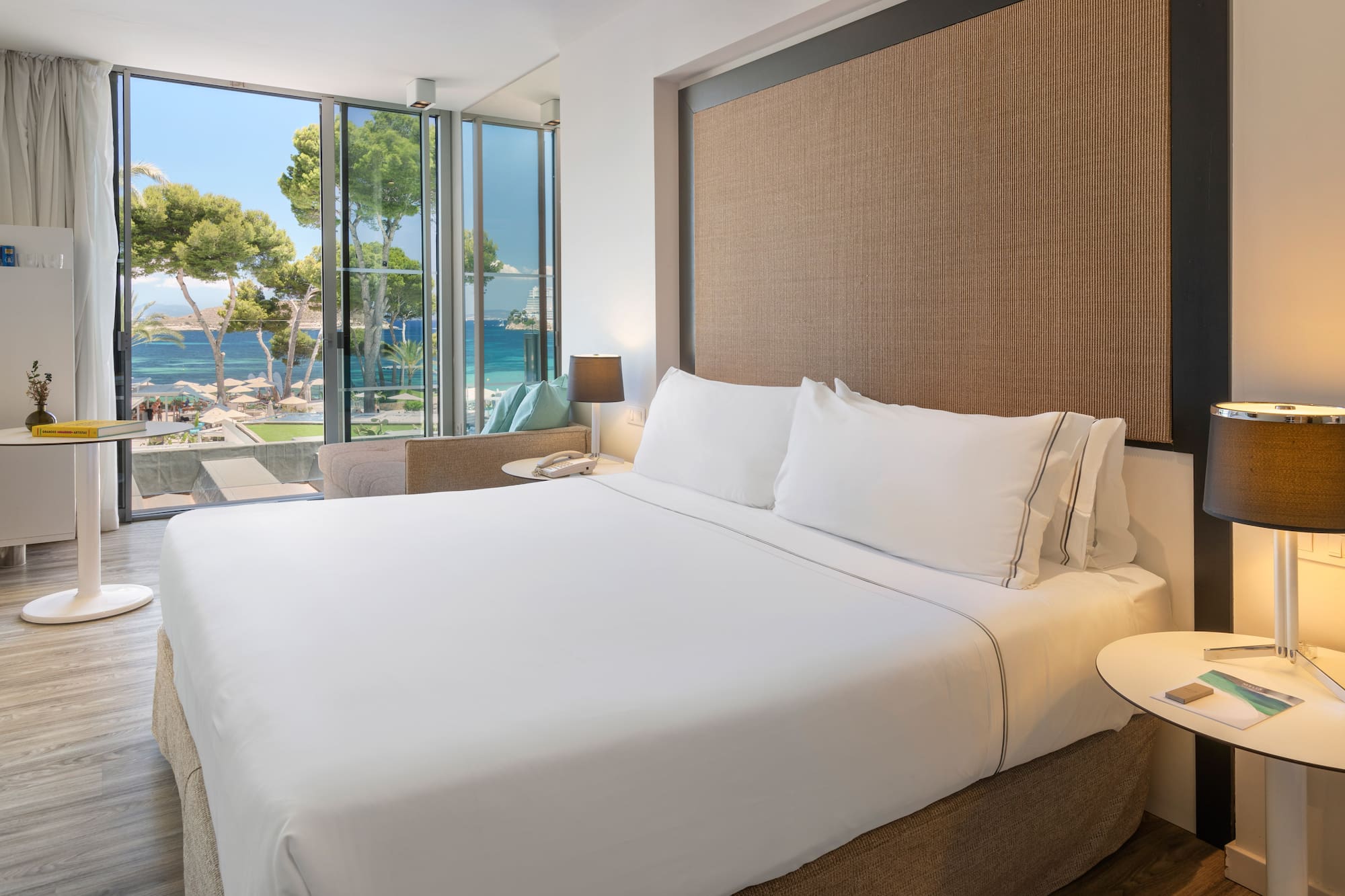 a bed with white sheets and a table next to a window