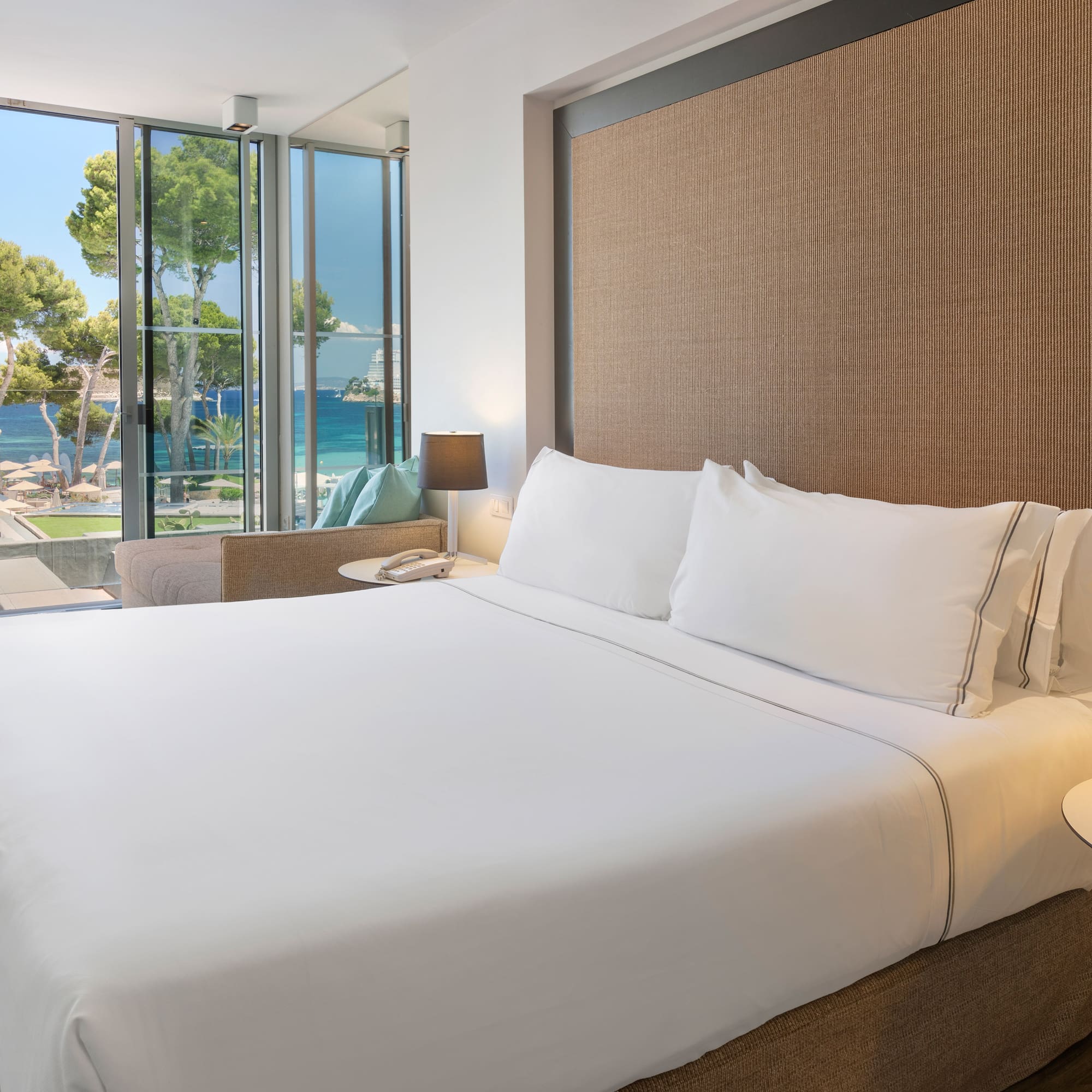 a bed with white sheets and a table next to a window