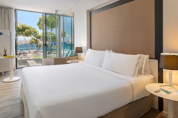 a bed with white sheets and a table next to a window