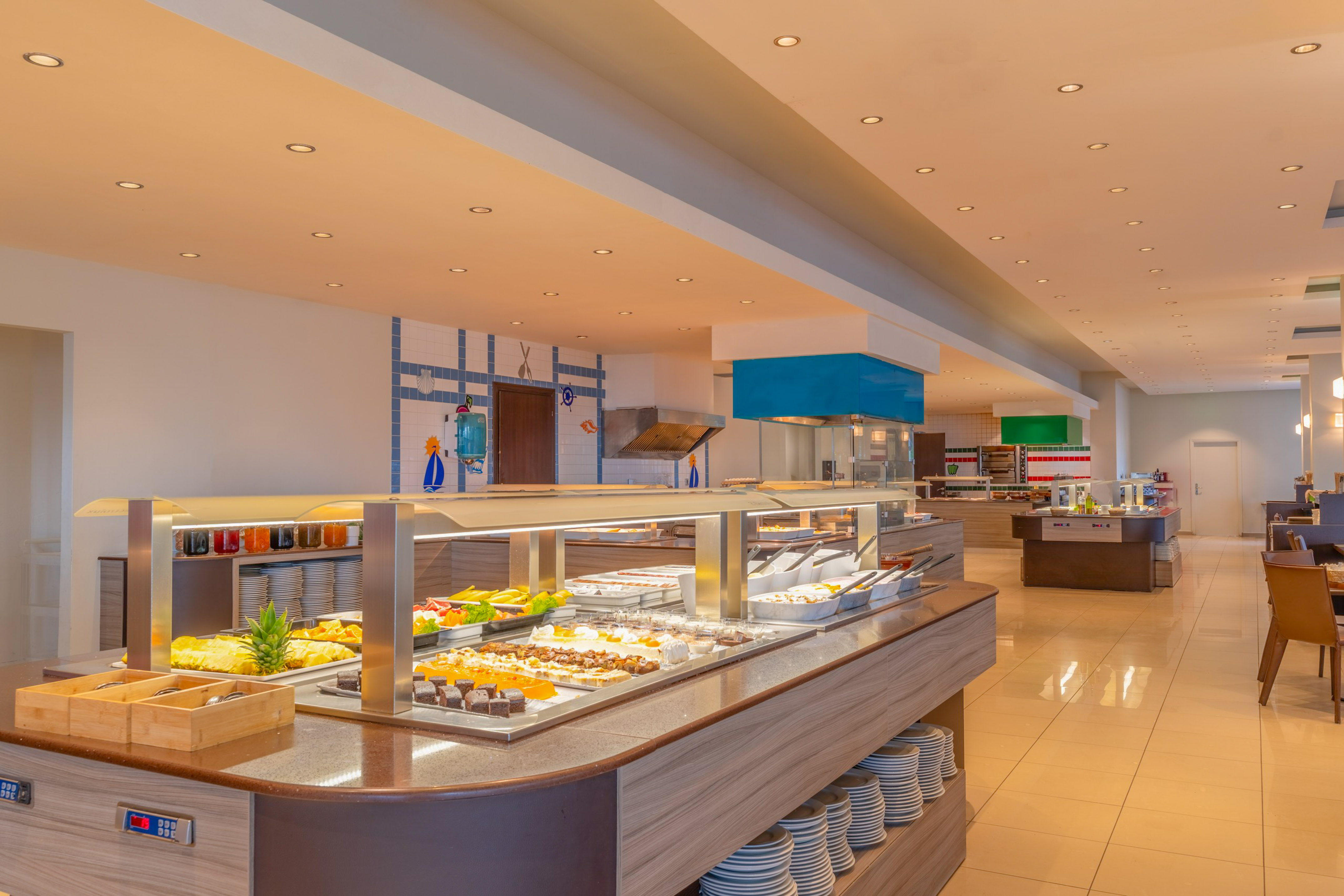 Bright hotel dining buffet featuring fresh food, fruits, and varied desserts.