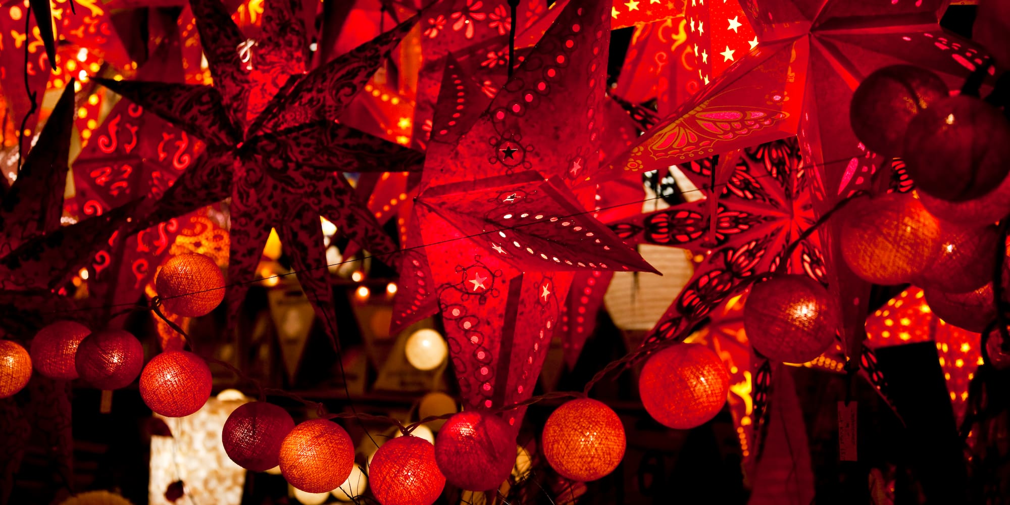 Vibrant red star paper lanterns and string lights for festive decor.