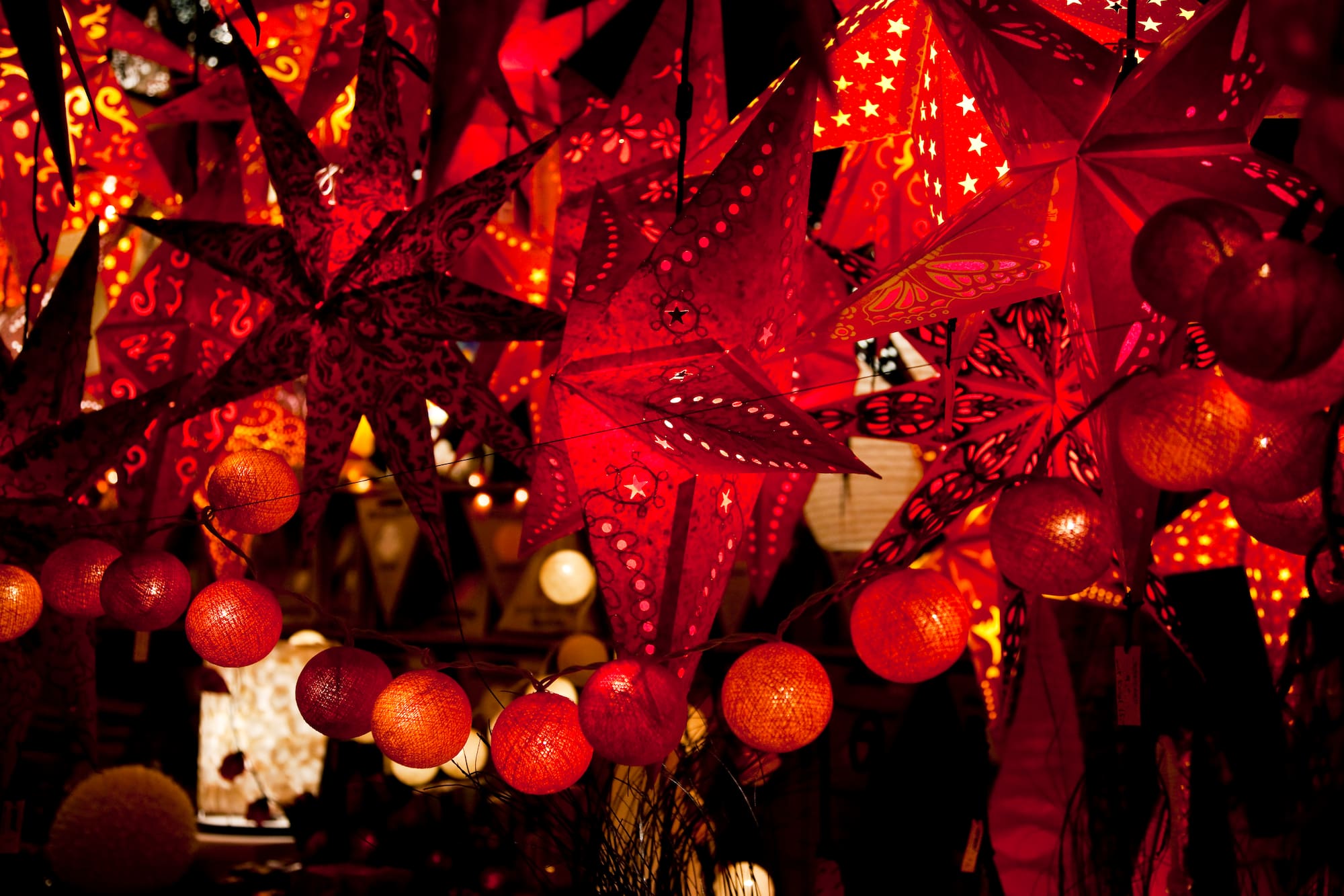 Estrellas rojas de papel iluminadas y guirnaldas de luces, decoración festiva brillante.
