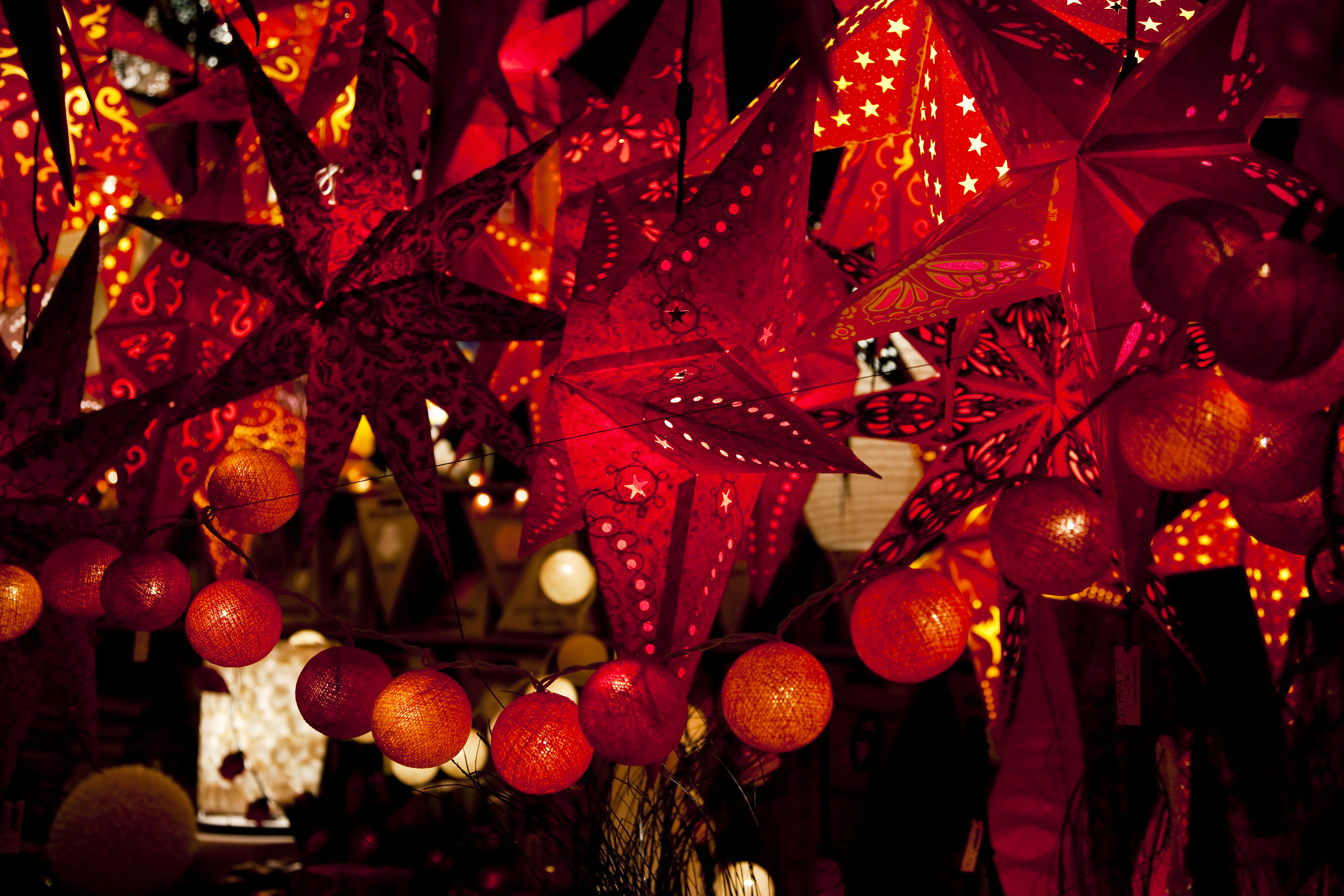 Vibrant red star paper lanterns and string lights for festive decor.