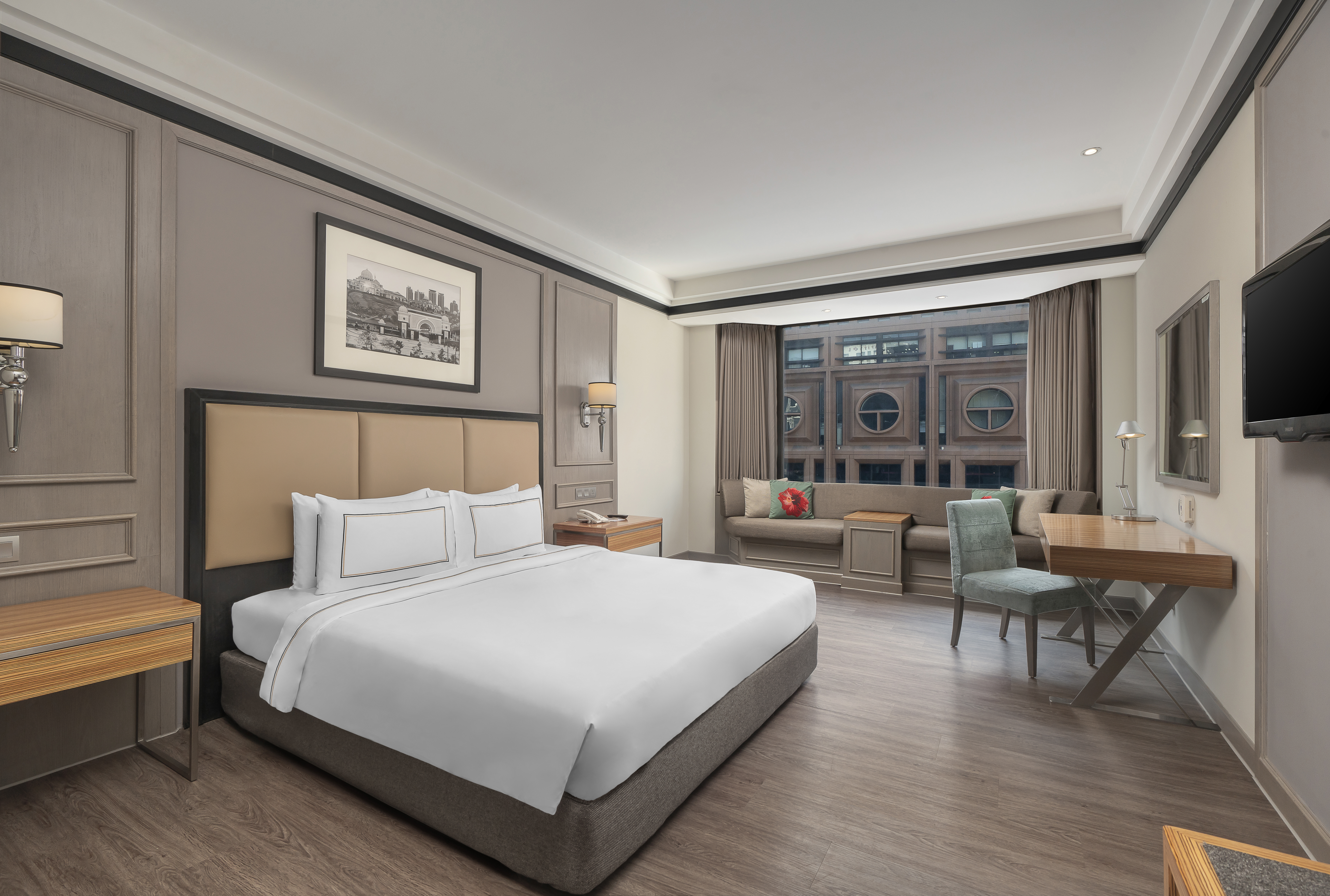 Modern hotel room with king bed, work desk, and window lounge area.