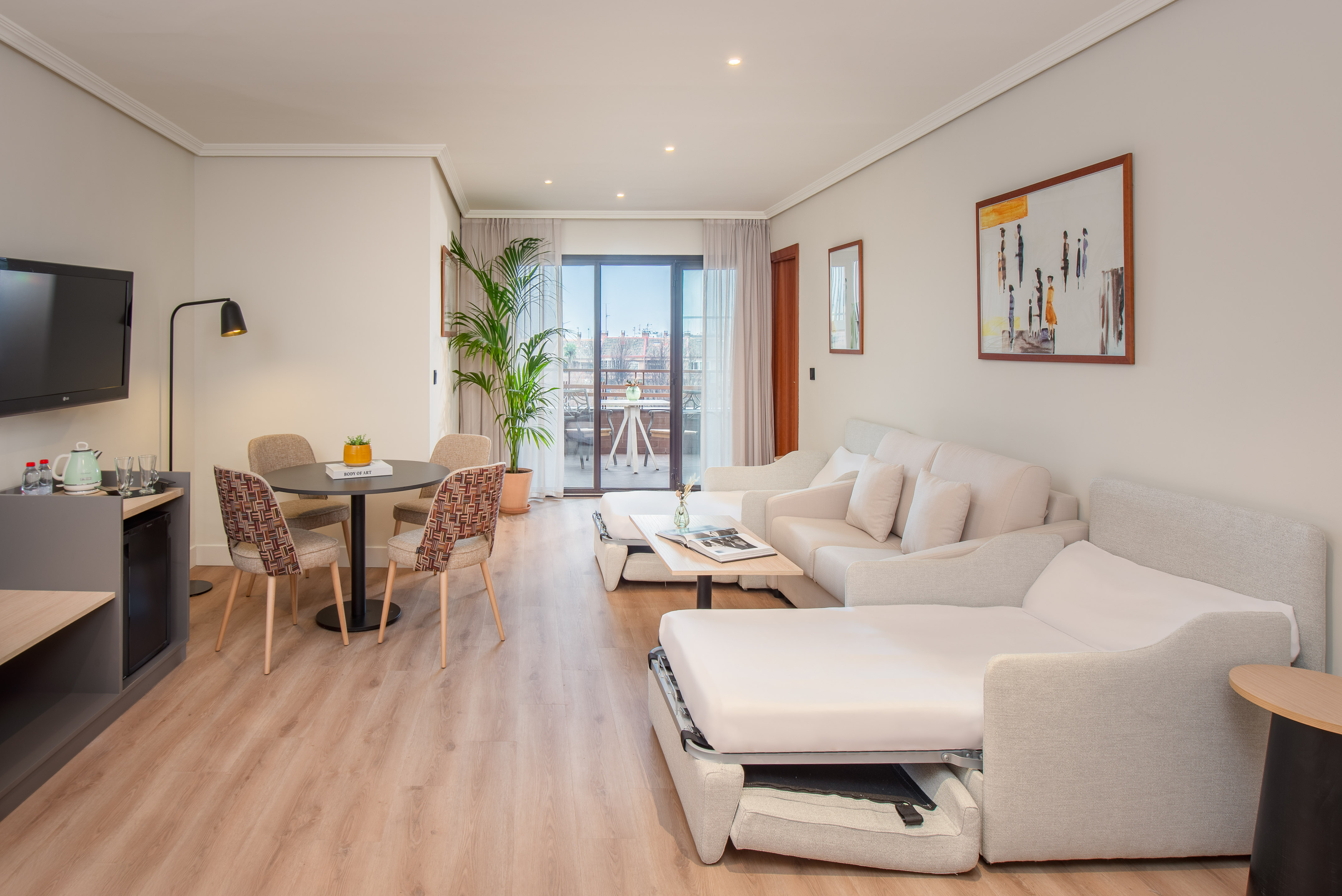 Modern apartment with open sofa bed, dining area, and balcony view.