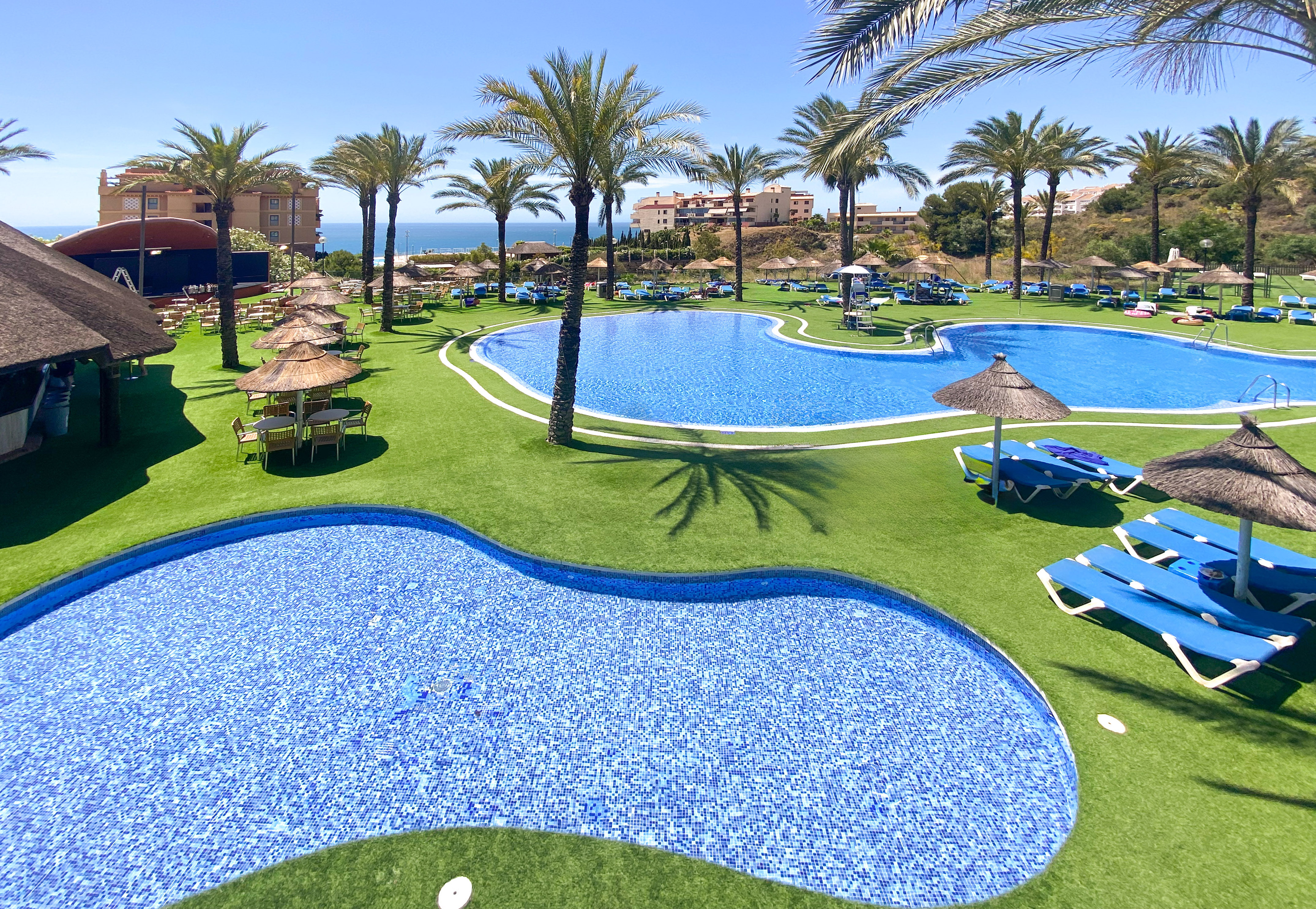 a pool with chairs and umbrellas on grass