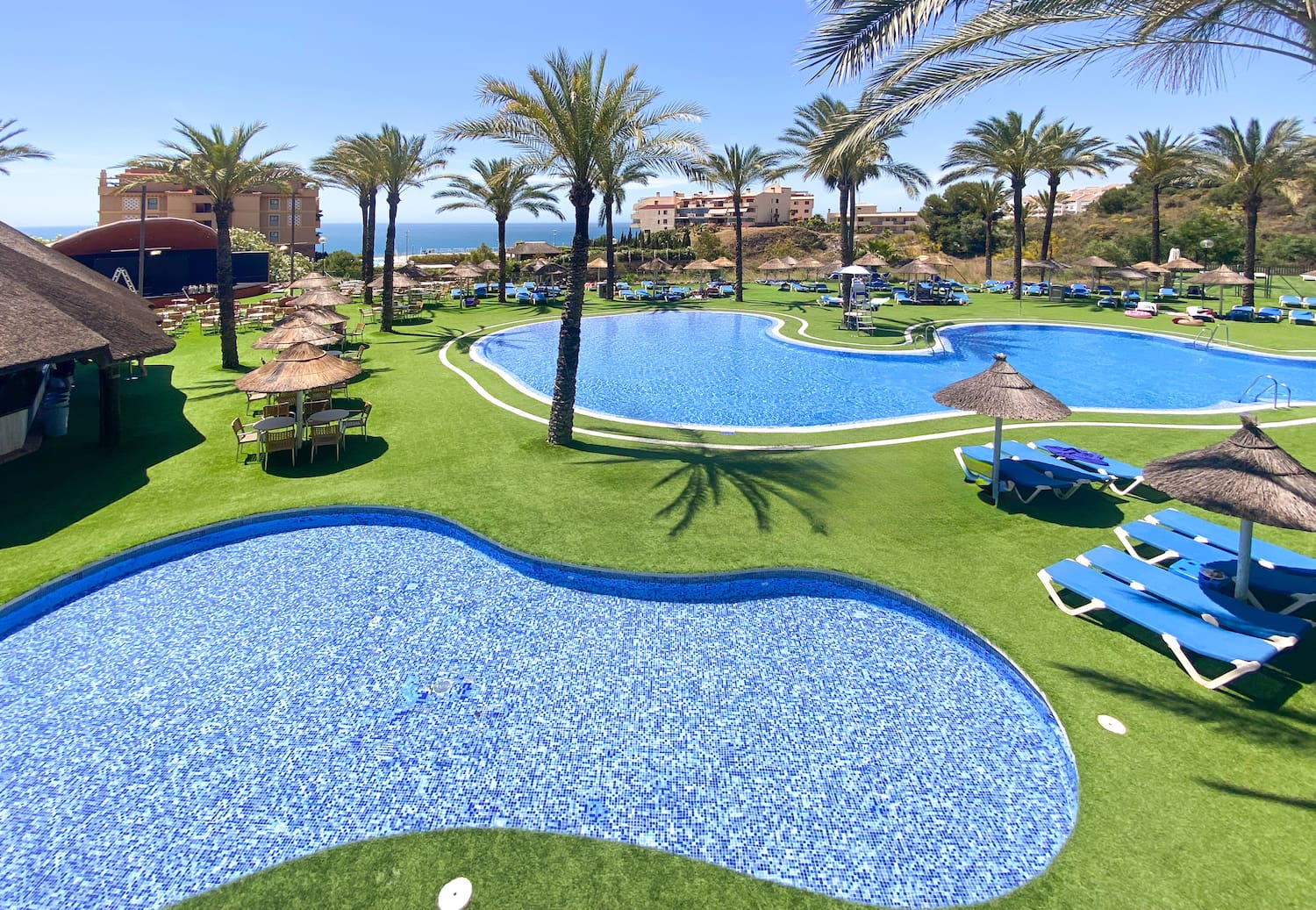 a pool with chairs and umbrellas on grass