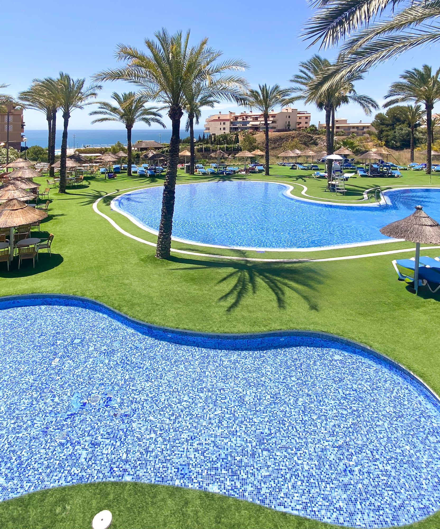 a pool with chairs and umbrellas on grass